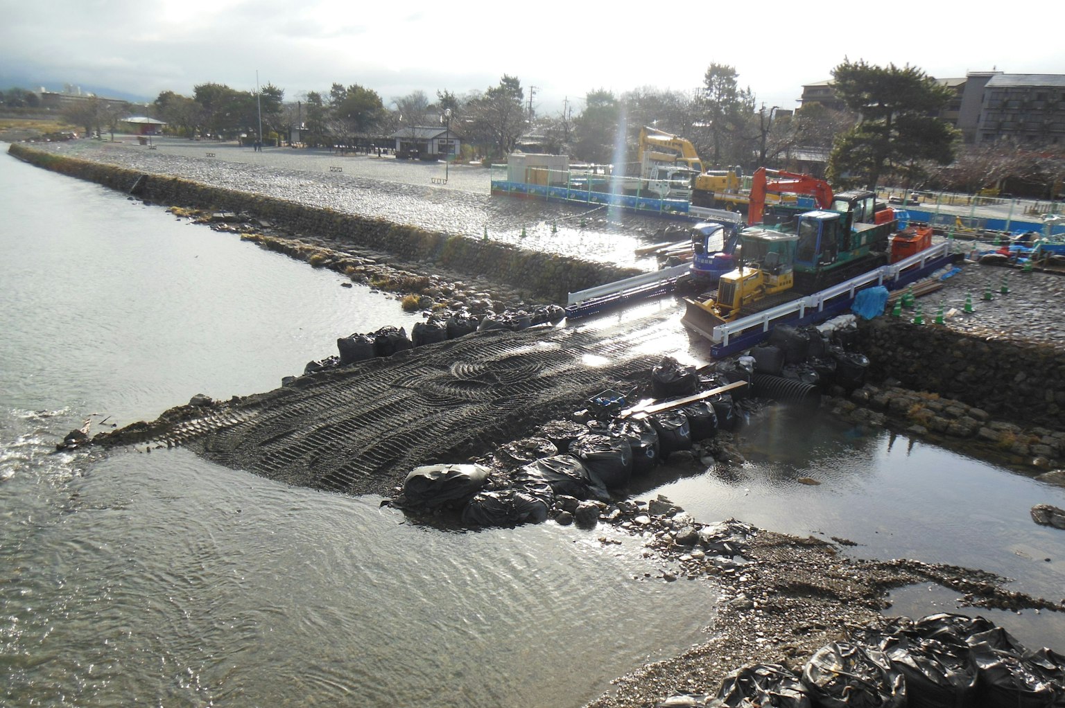 Cantiere di costruzione lungo il fiume con macchinari in azione