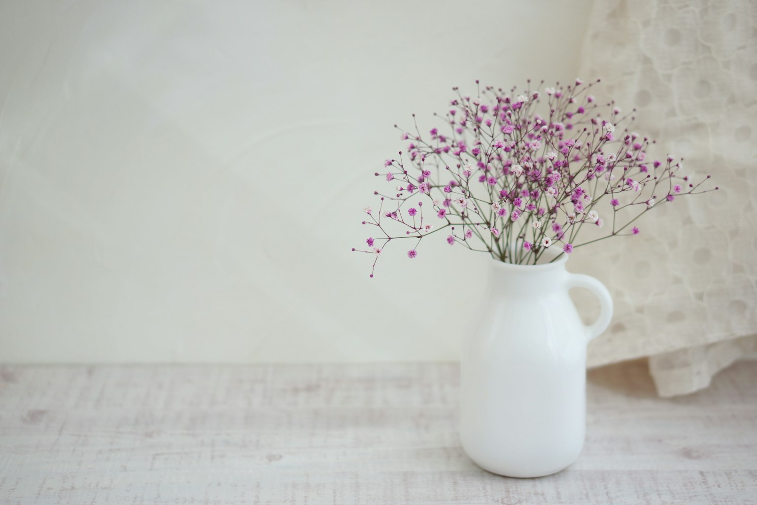 하얀 꽃병에 작은 보라색 꽃이 담긴 간단하고 아름다운 장식