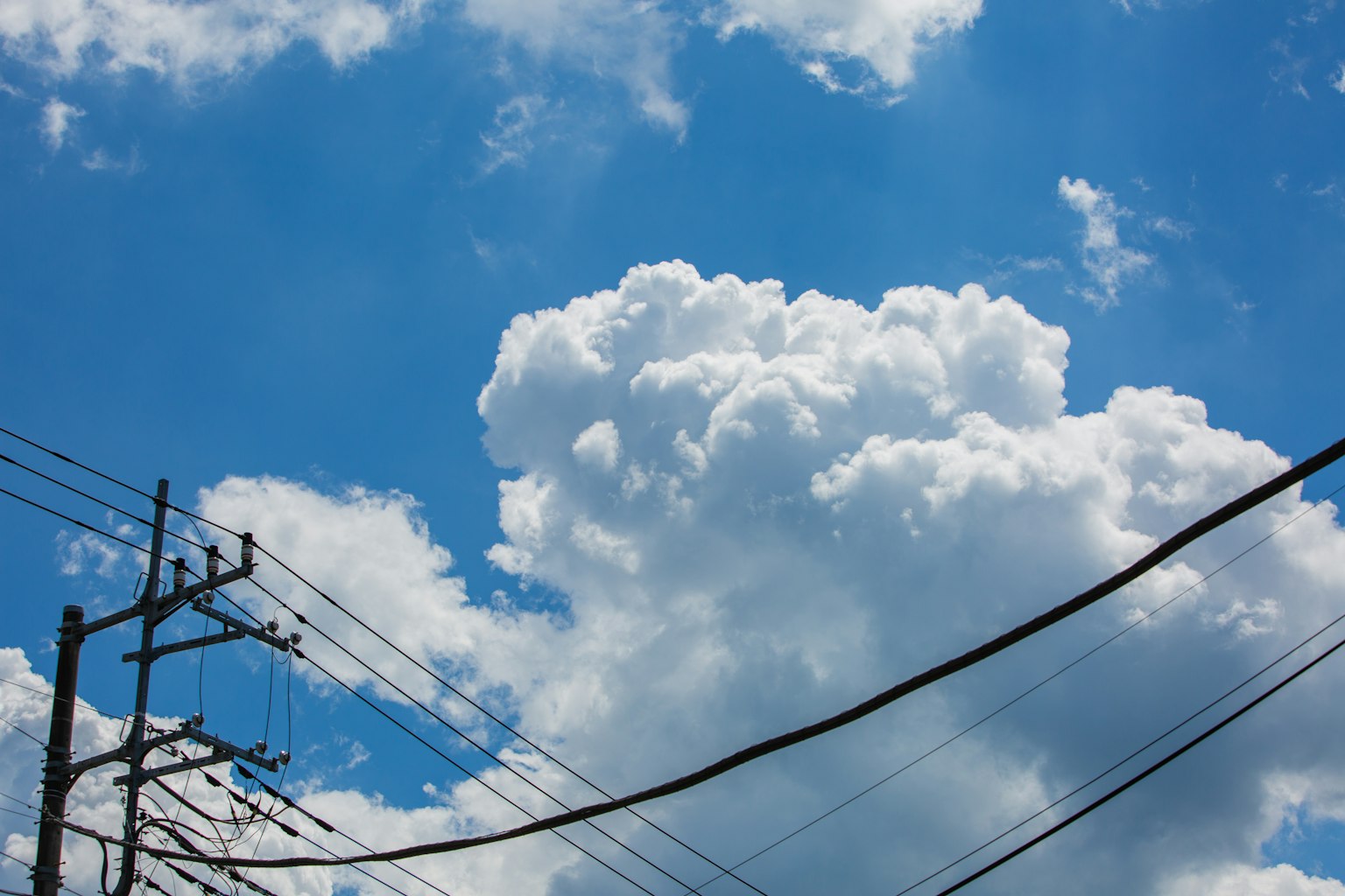Un ciel bleu clair avec des nuages blancs et des lignes électriques