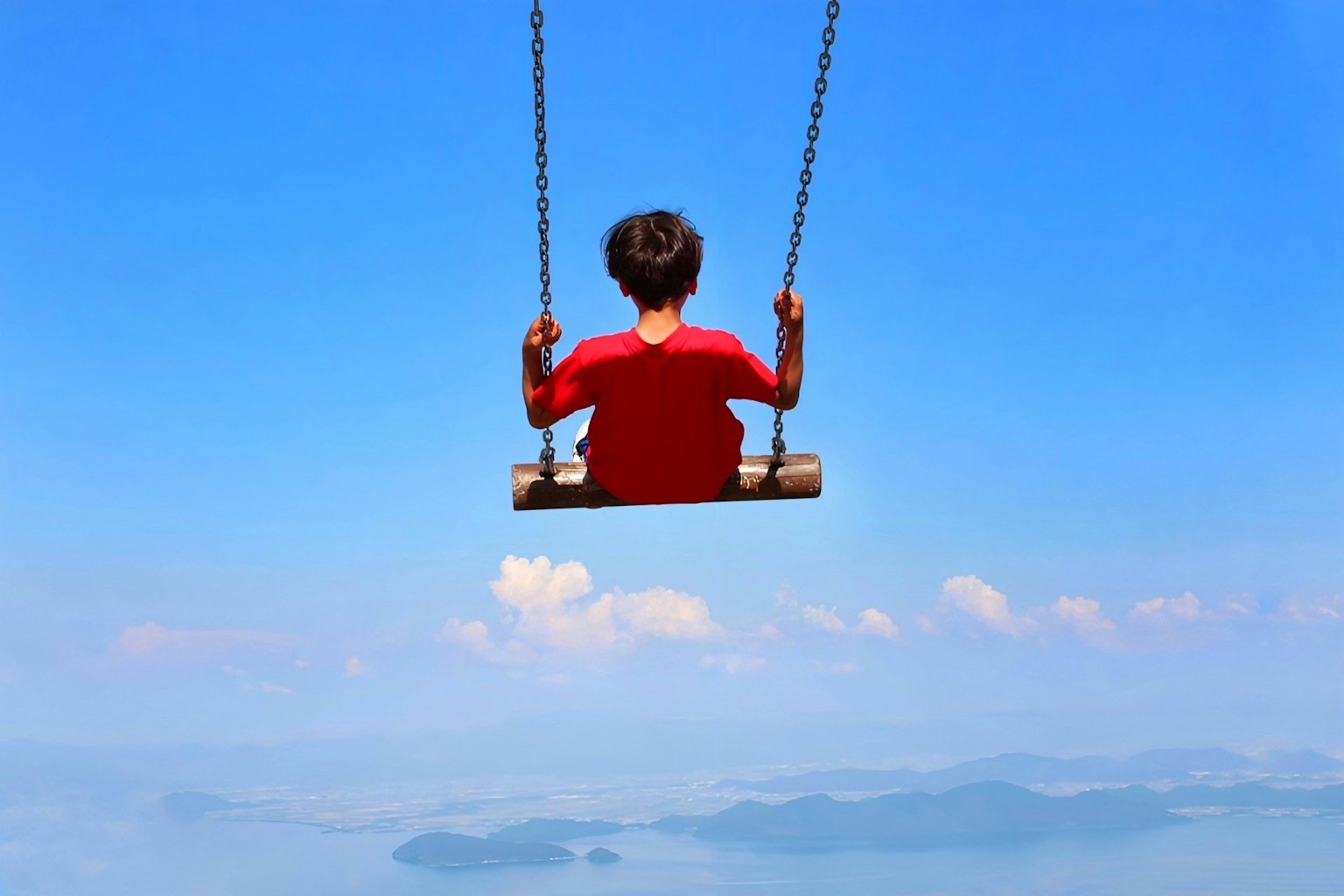 Enfant sur une balançoire sous un ciel bleu lumineux