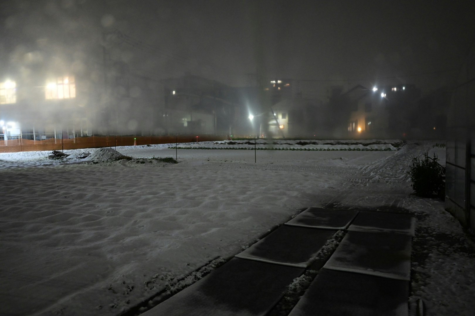 snow-covered plaza and streetlights at night