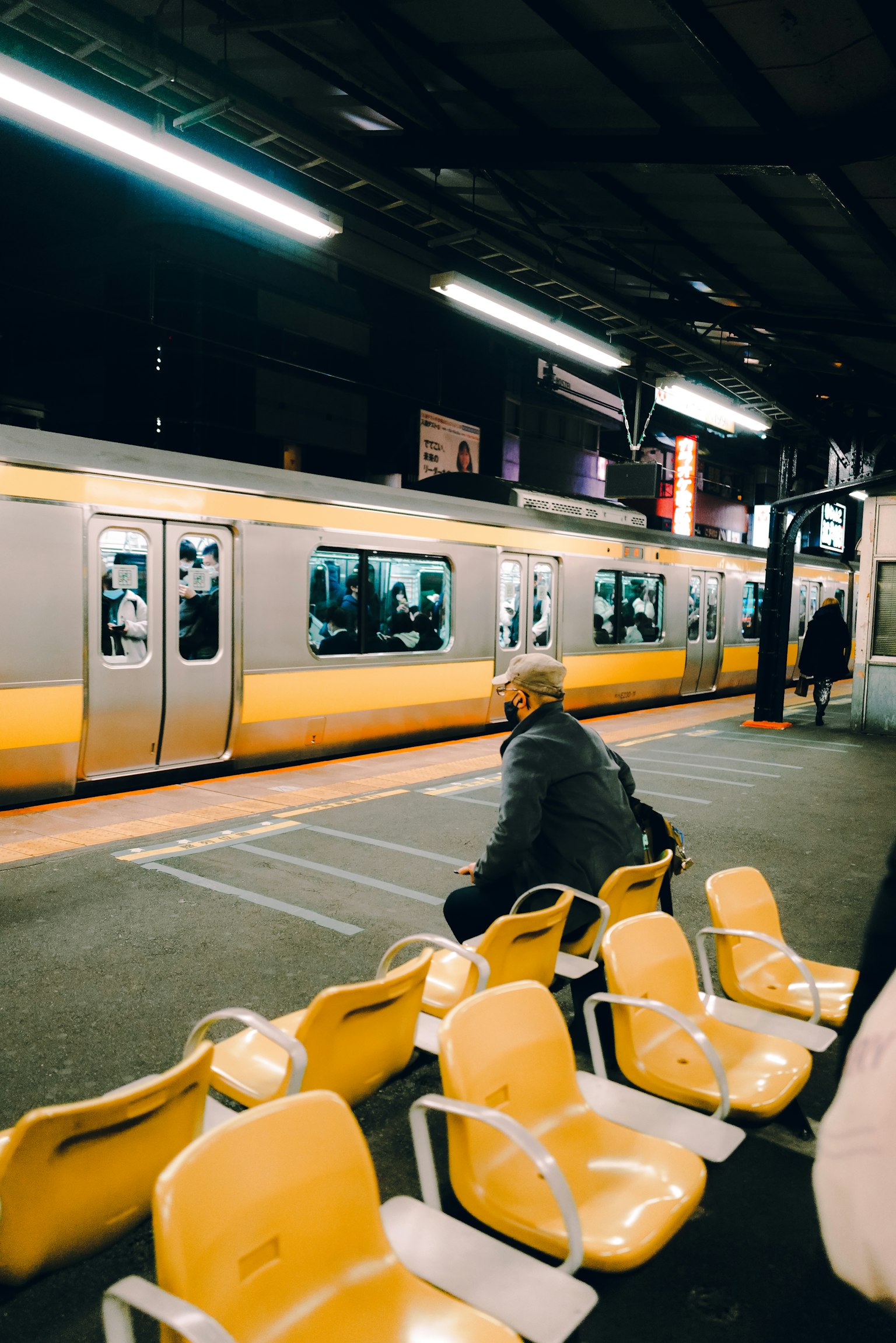 Kereta di platform stasiun dengan seorang pria duduk di kursi kuning