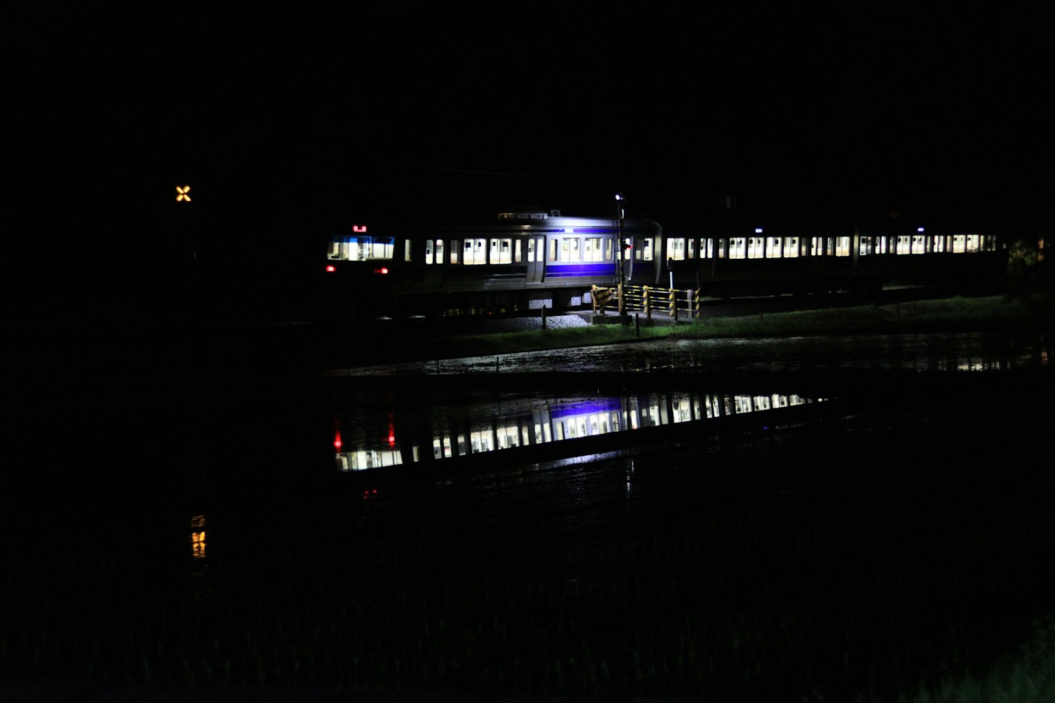 Train illuminated at night reflecting in water