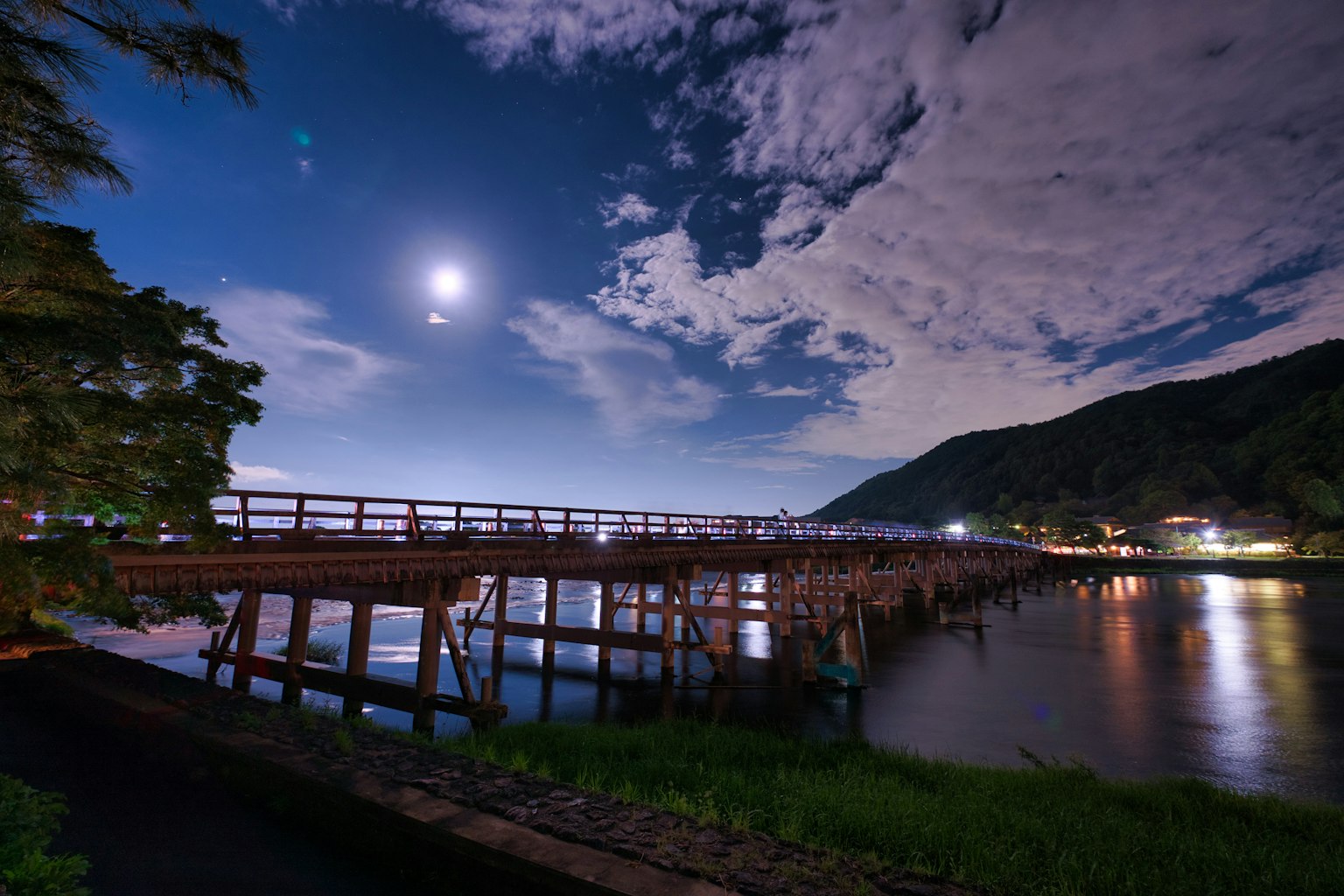 Un lago sereno sotto la luna con un lungo ponte in legno
