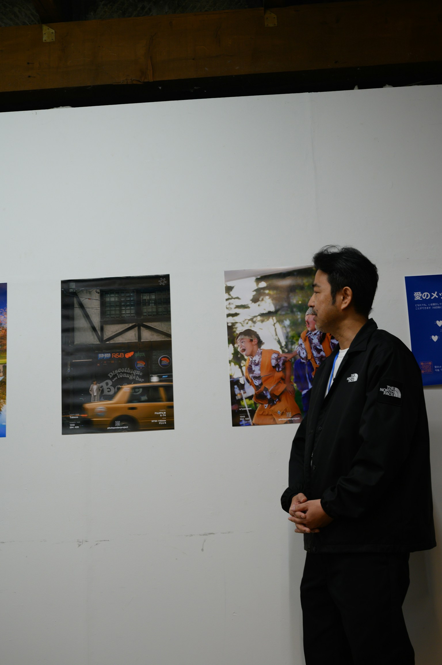 A man observing photographs at an exhibition featuring images of taxis and people on the wall