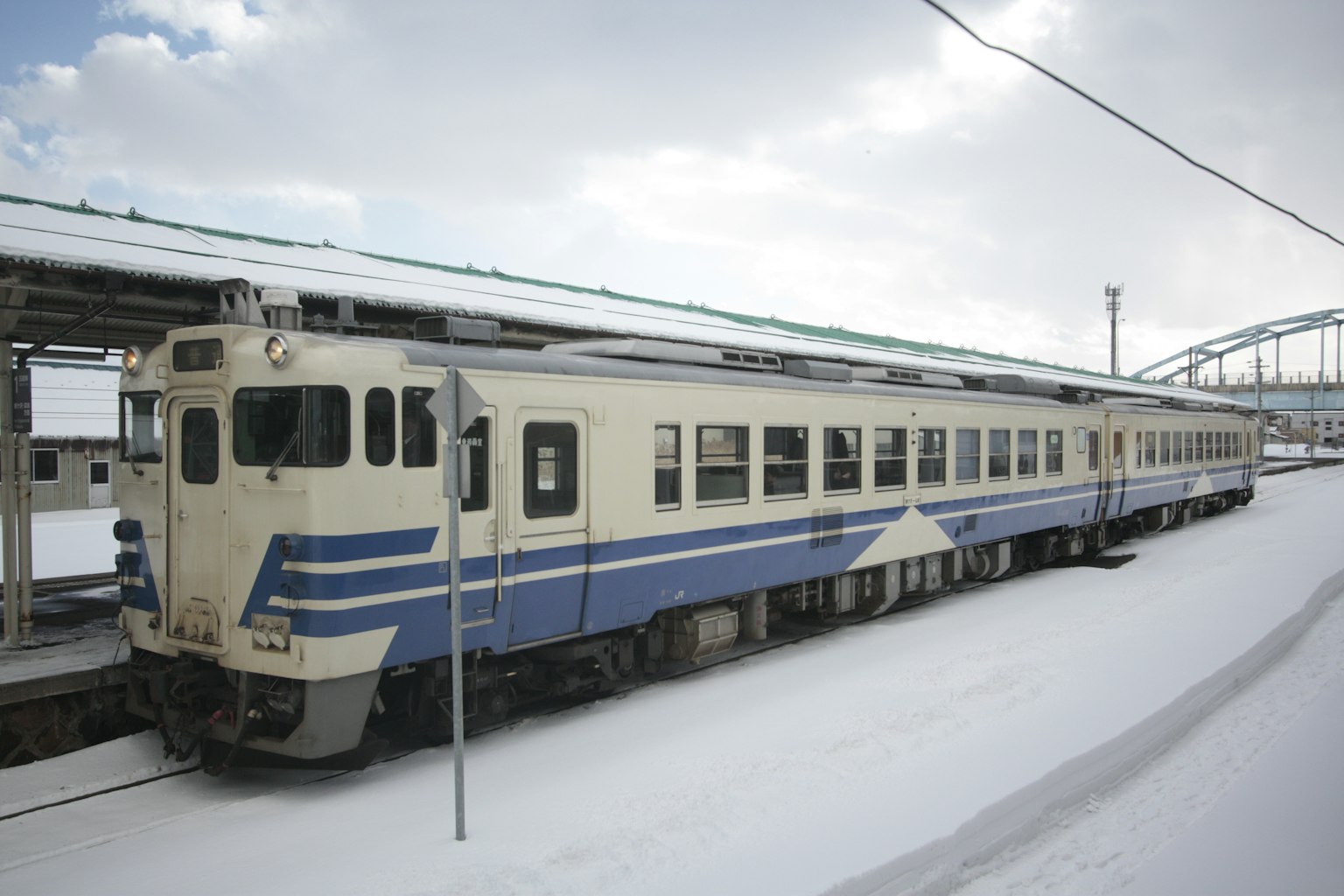 Blue and white train stopped at a snow-covered station