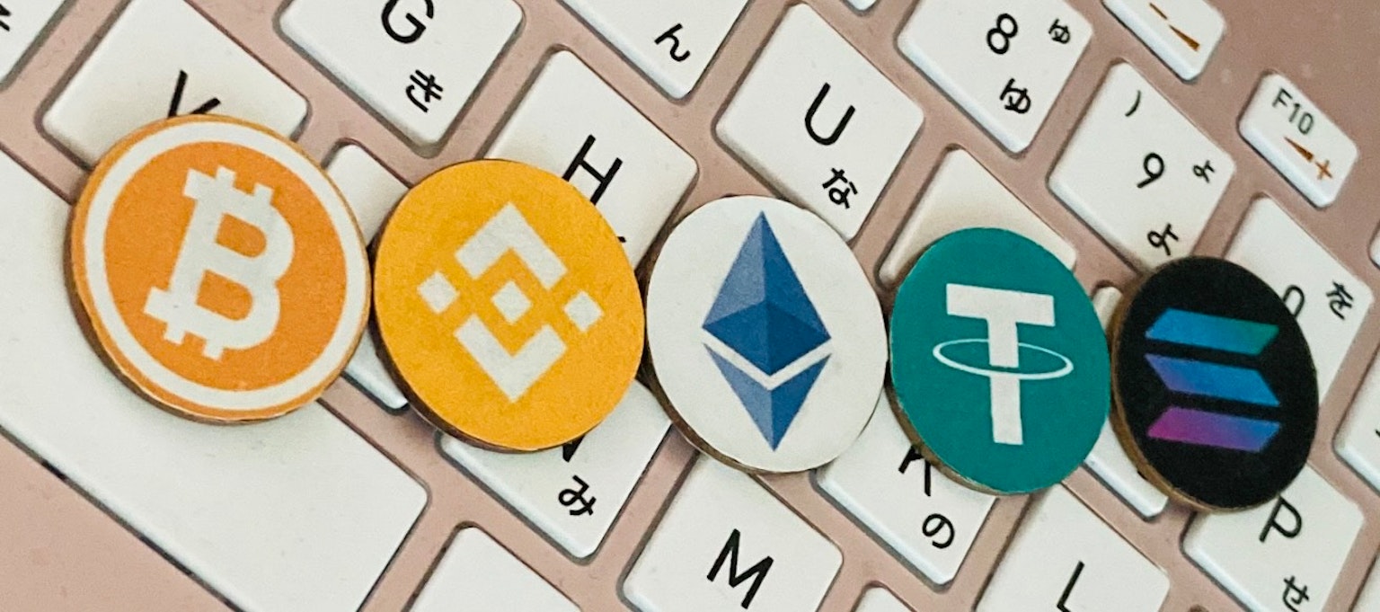 Pièces de Bitcoin, Binance, Ethereum, Tether et Solana disposées sur un clavier