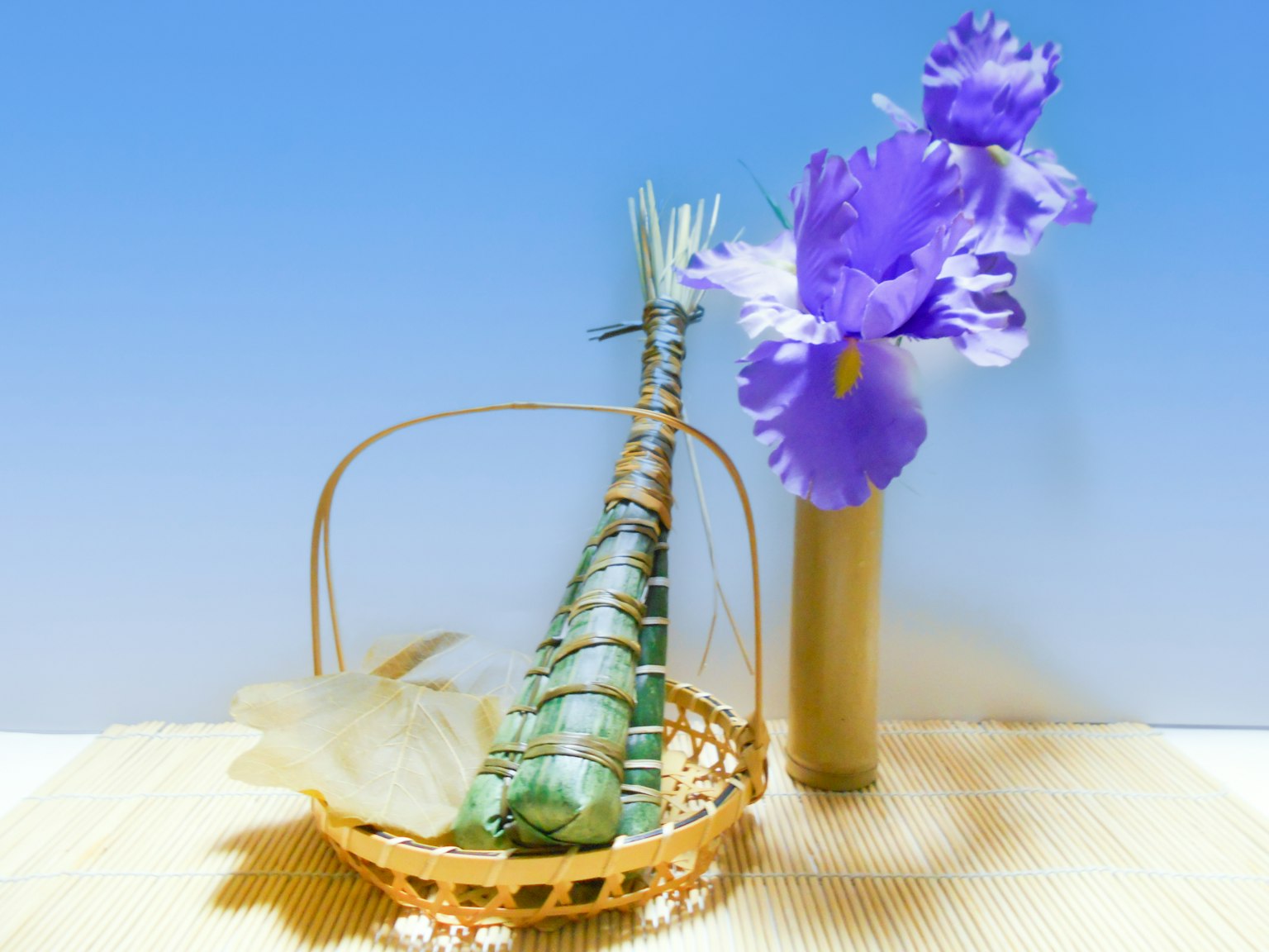 Un panier avec un objet en bambou et des fleurs violettes sur fond de ciel bleu