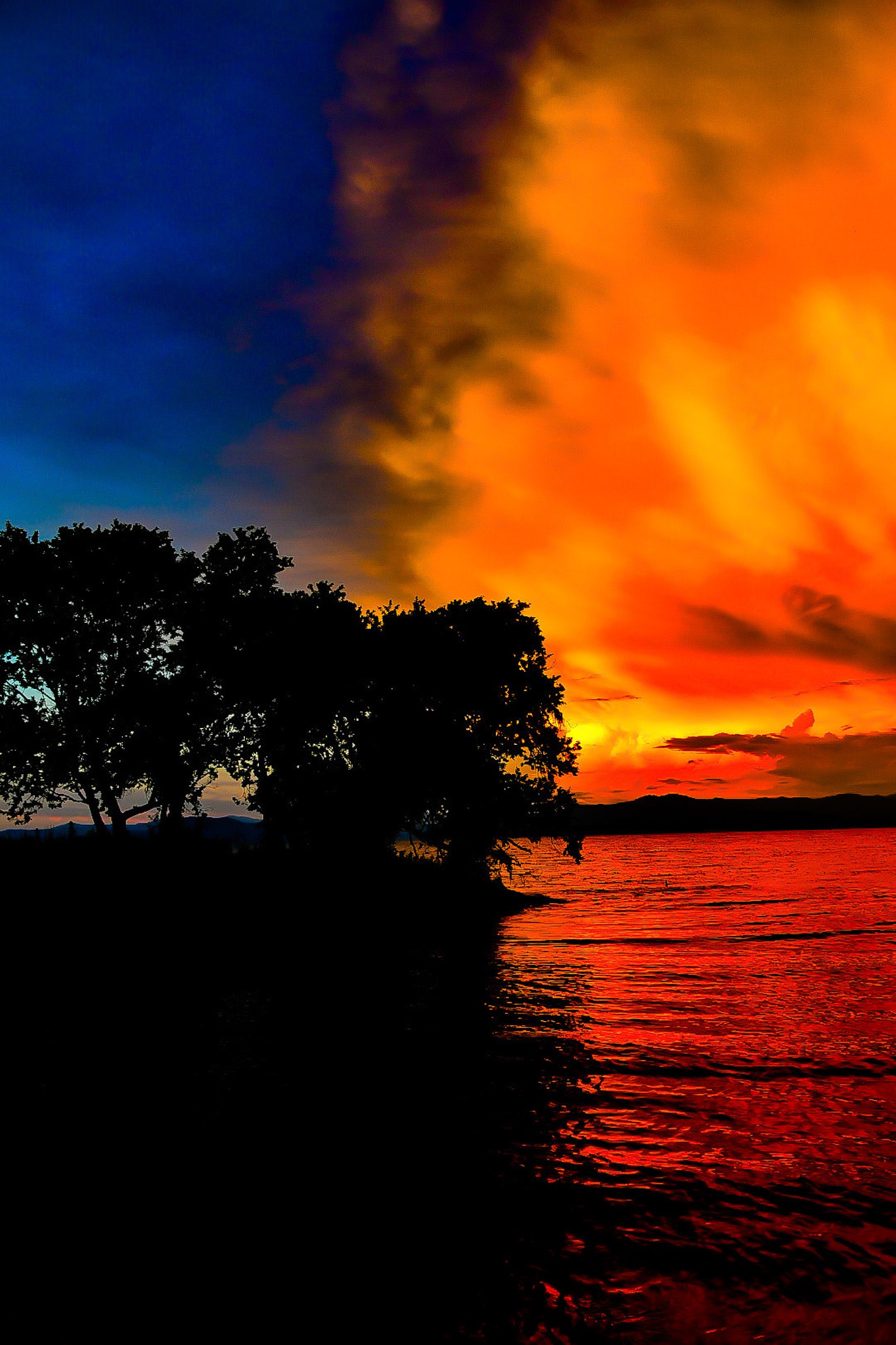 Coucher de soleil magnifique avec un ciel orange et bleu vibrant se reflétant sur l'eau