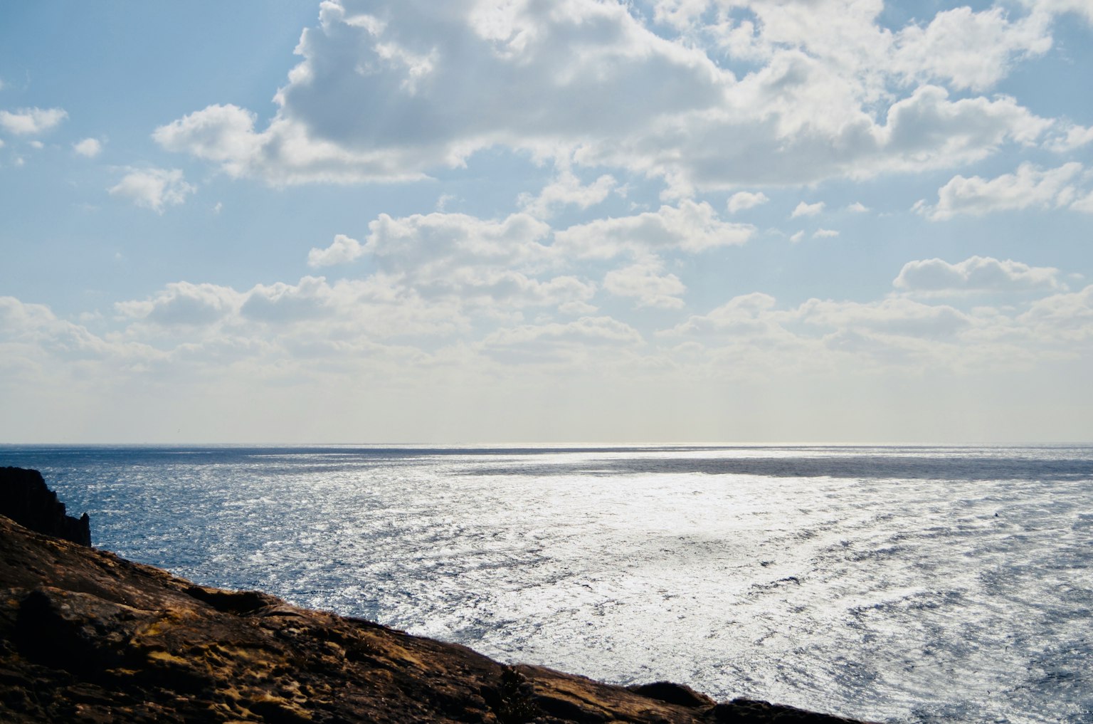 Panoramablick auf den blauen Ozean und den bewölkten Himmel von der Felsenbucht