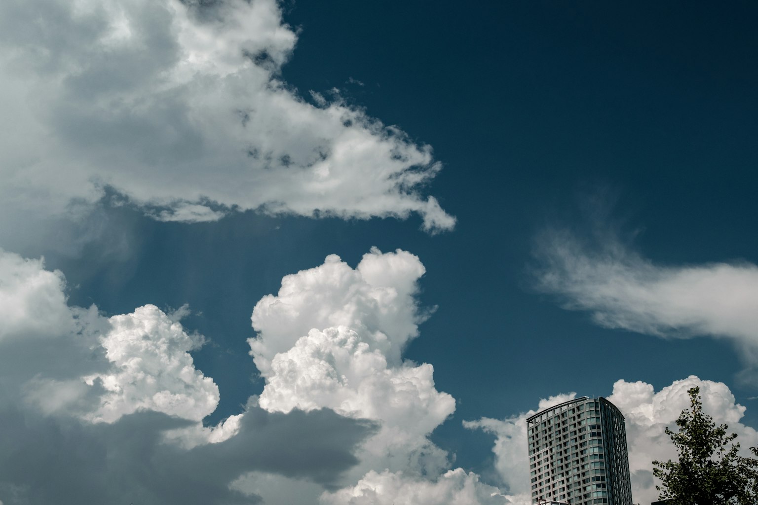 Una vista de un cielo azul con nubes blancas y un rascacielos