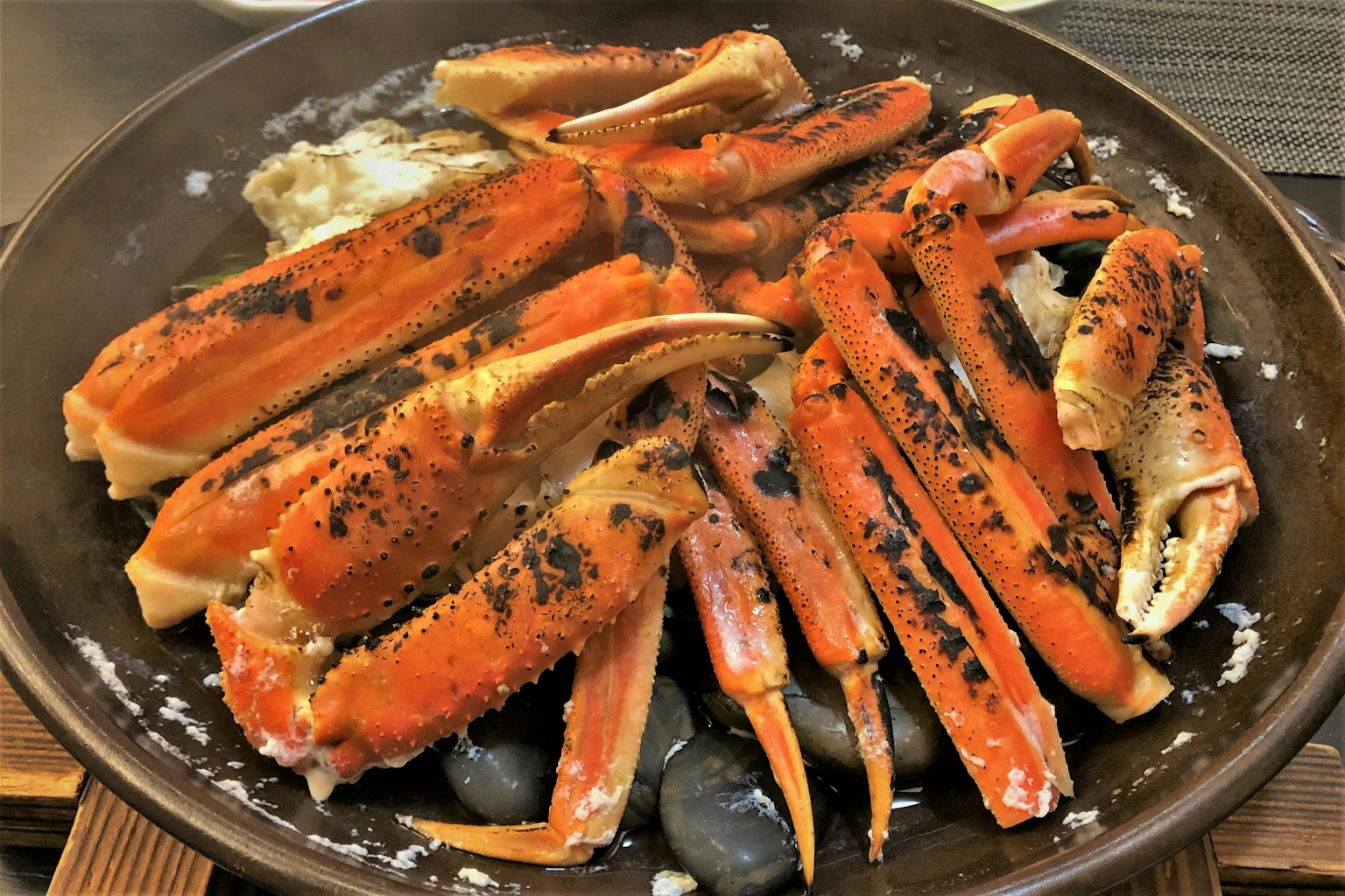 烧烤螃蟹菜肴，红色螃蟹腿和肉，放在黑色石头上