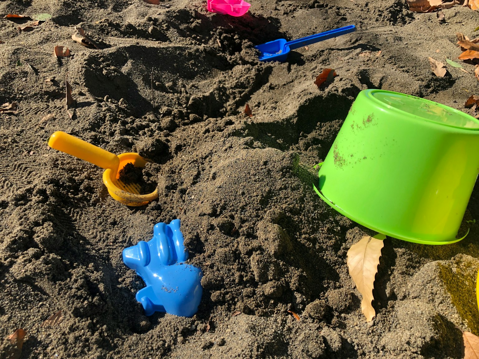 Jouets colorés pour jouer dans le sable enfouis dans un bac à sable