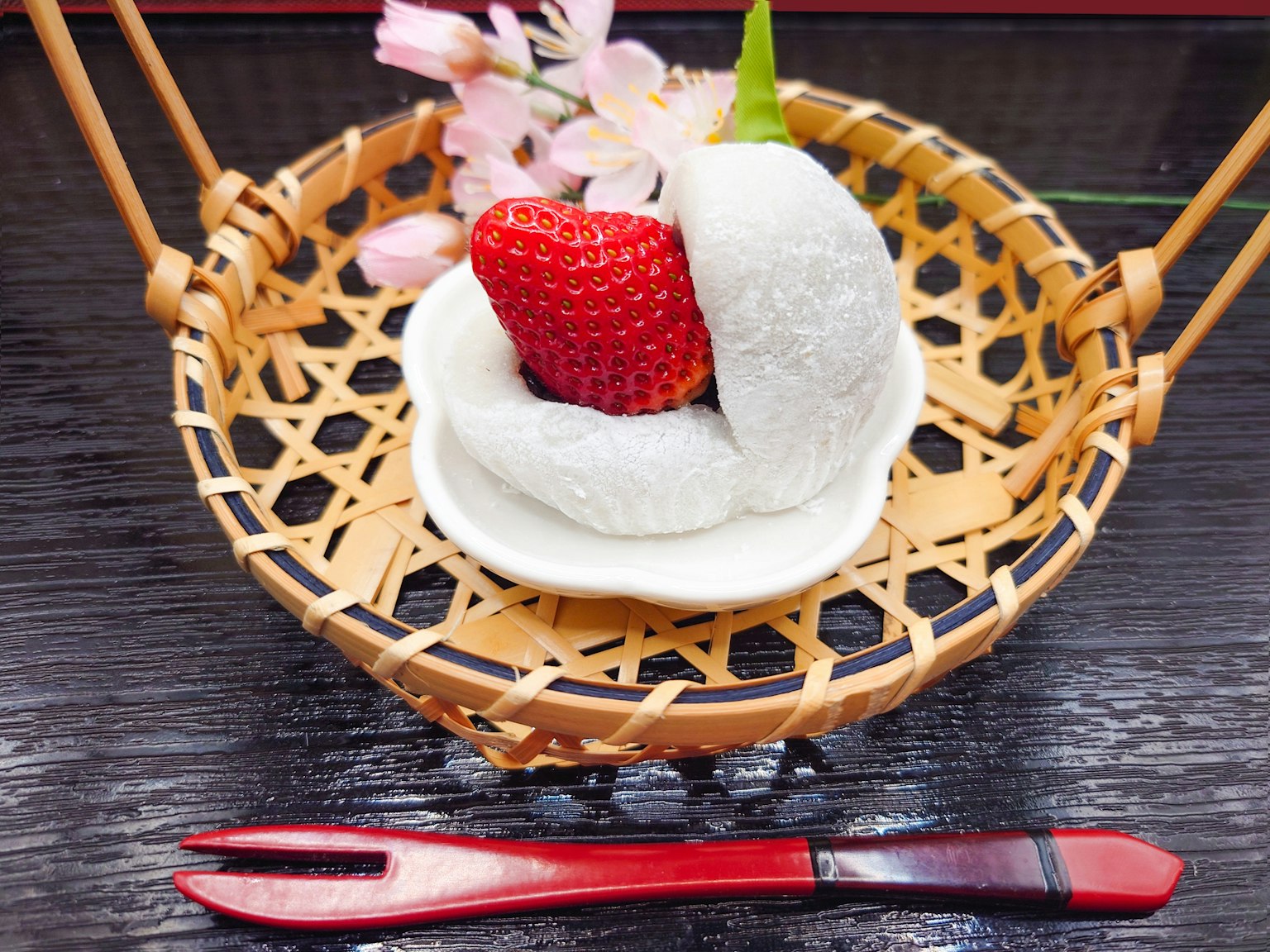 Daifuku stroberi disajikan dalam keranjang bambu dengan bunga