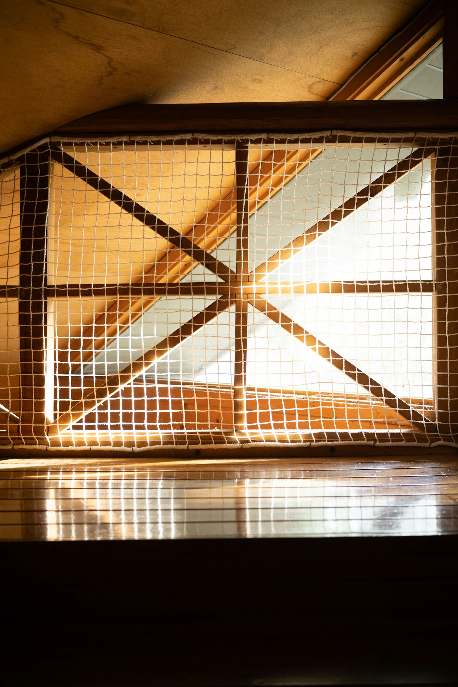 木製の手すりと光が差し込む窓のある屋根裏部屋の内部