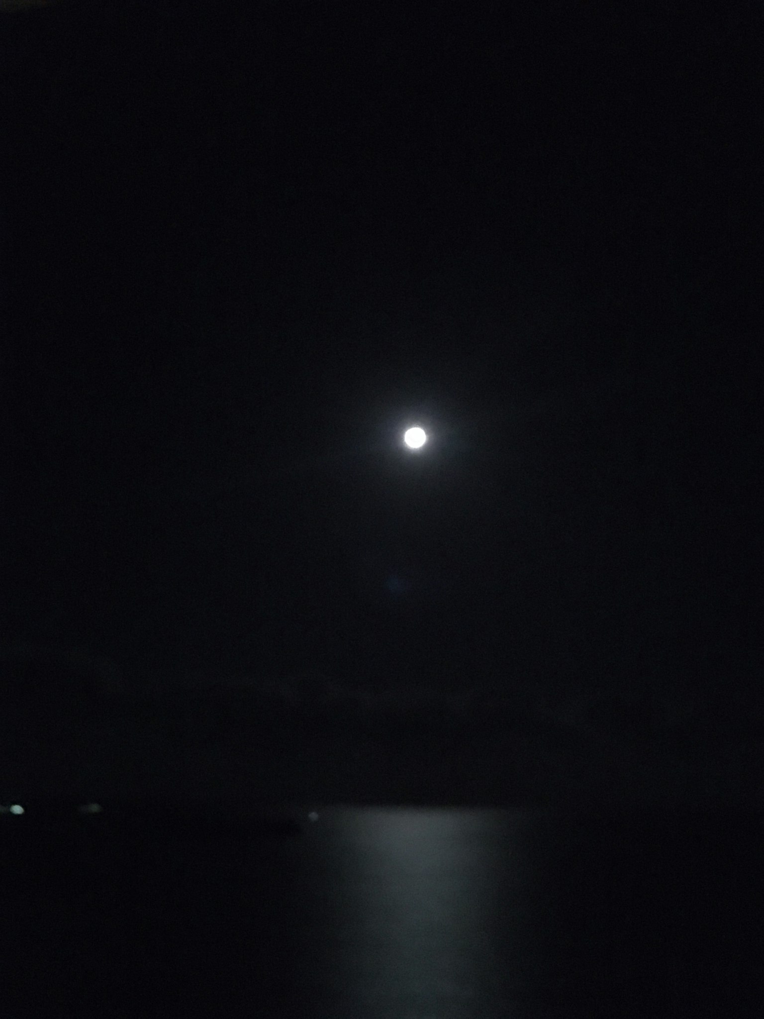 夜空中明亮的滿月及其在水面上的反射