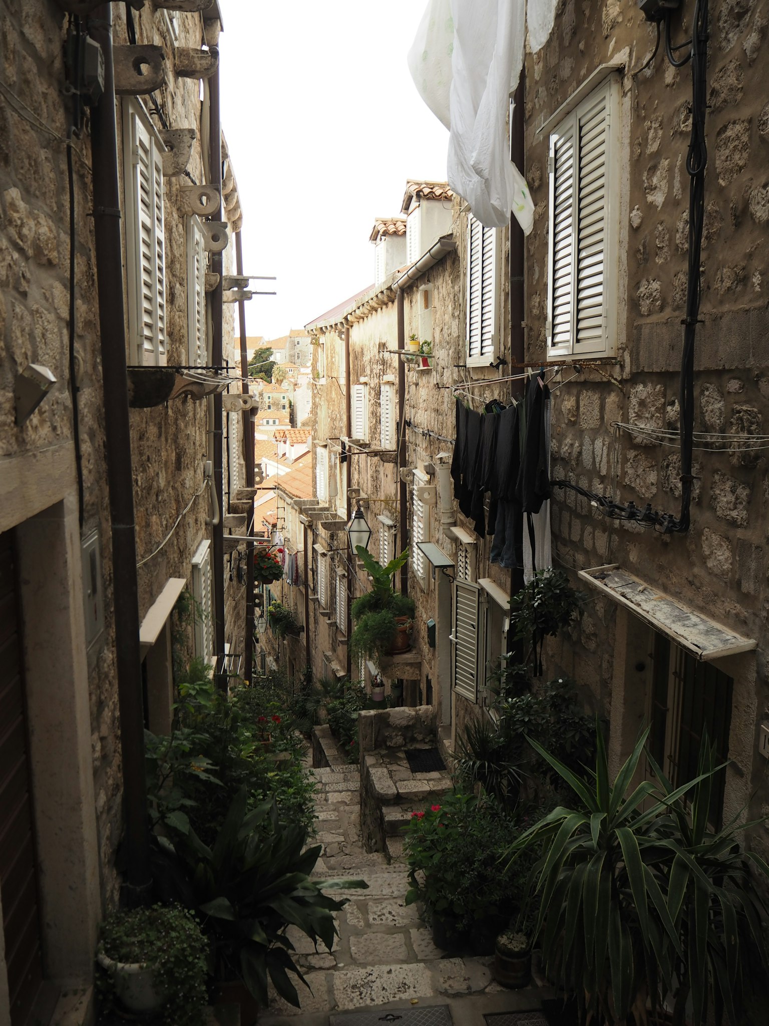Stretto vicolo in pietra con piante e biancheria stesa