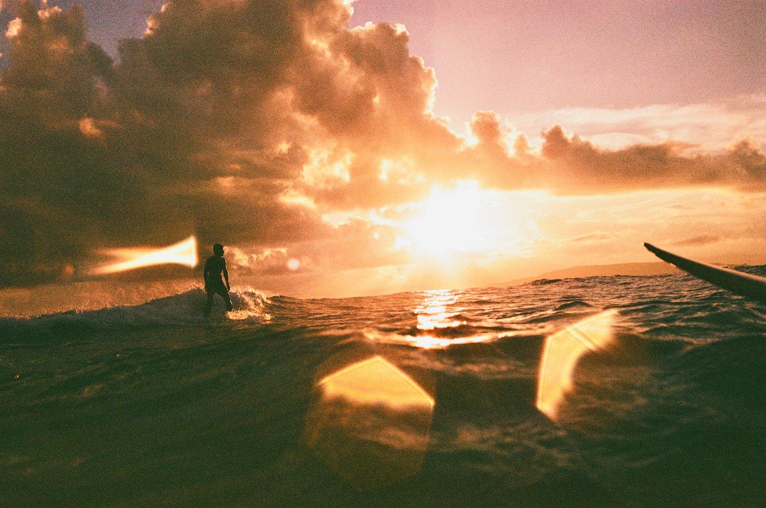 Surfista che si gode il tramonto sull'oceano con nuvole nel cielo