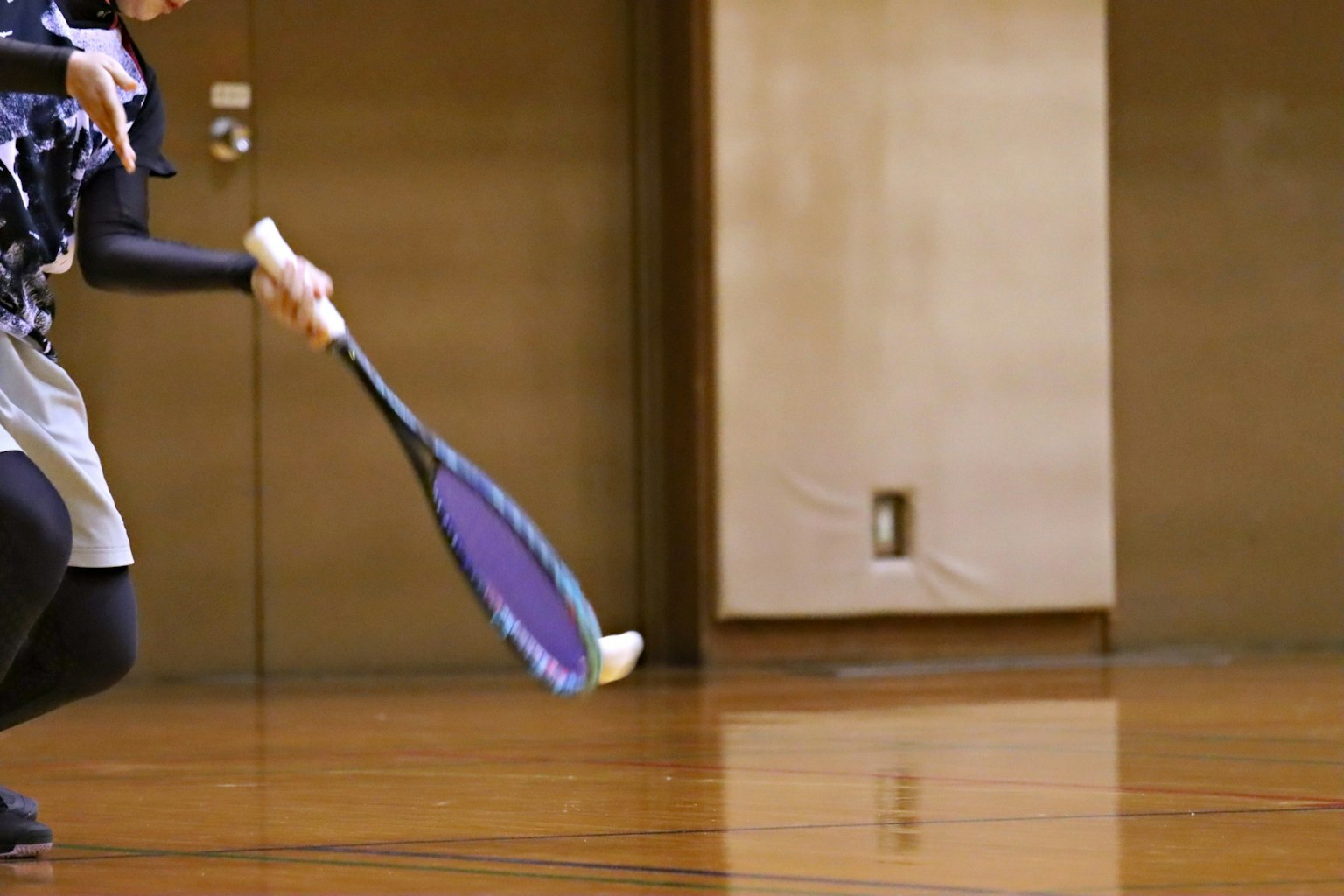 Un giocatore che tiene una racchetta da badminton in azione sul campo
