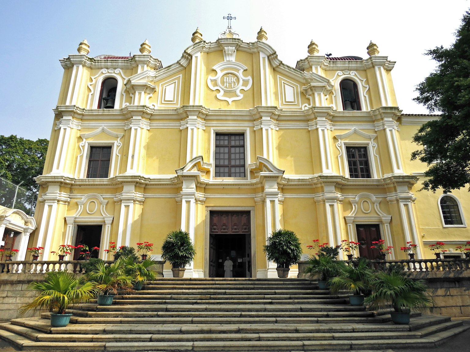Facciata di chiesa storica con esterno giallo scale e vegetazione