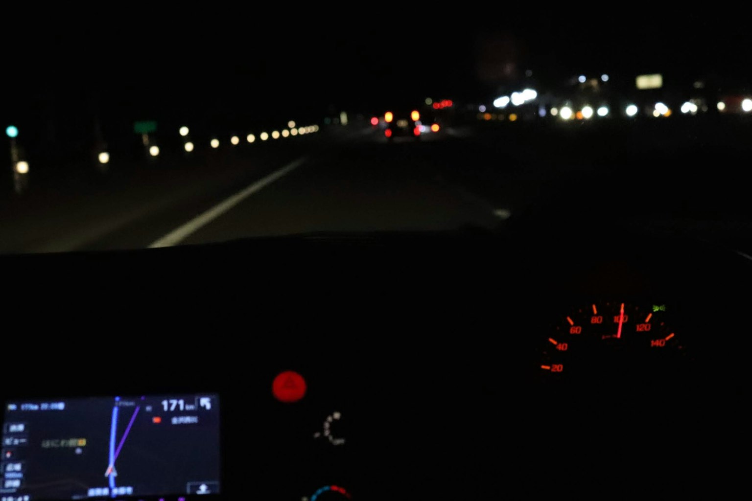 Tampilan interior mobil yang melaju di jalan raya di malam hari dengan layar navigasi