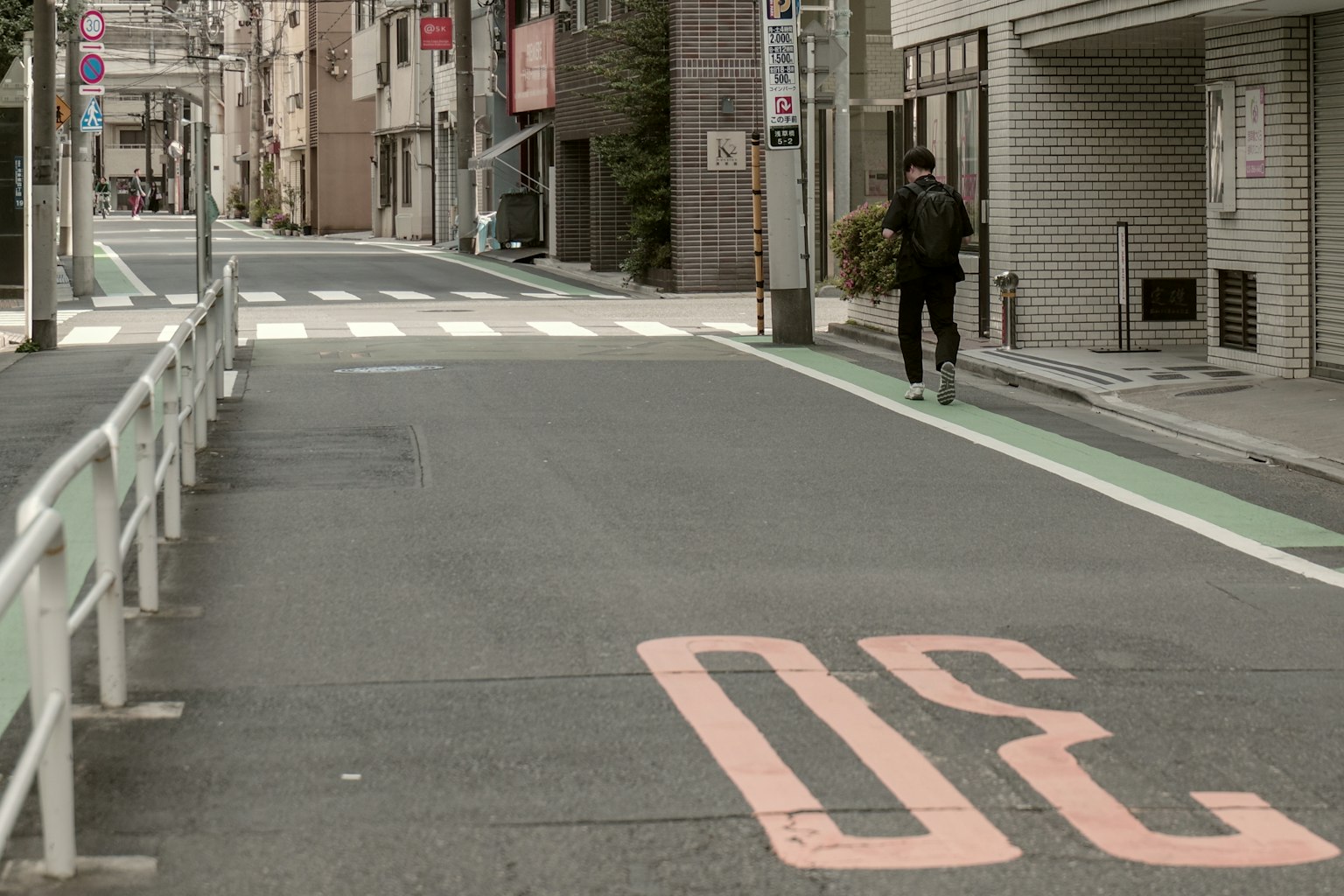 A person running on a quiet street with the number 30 painted on the road