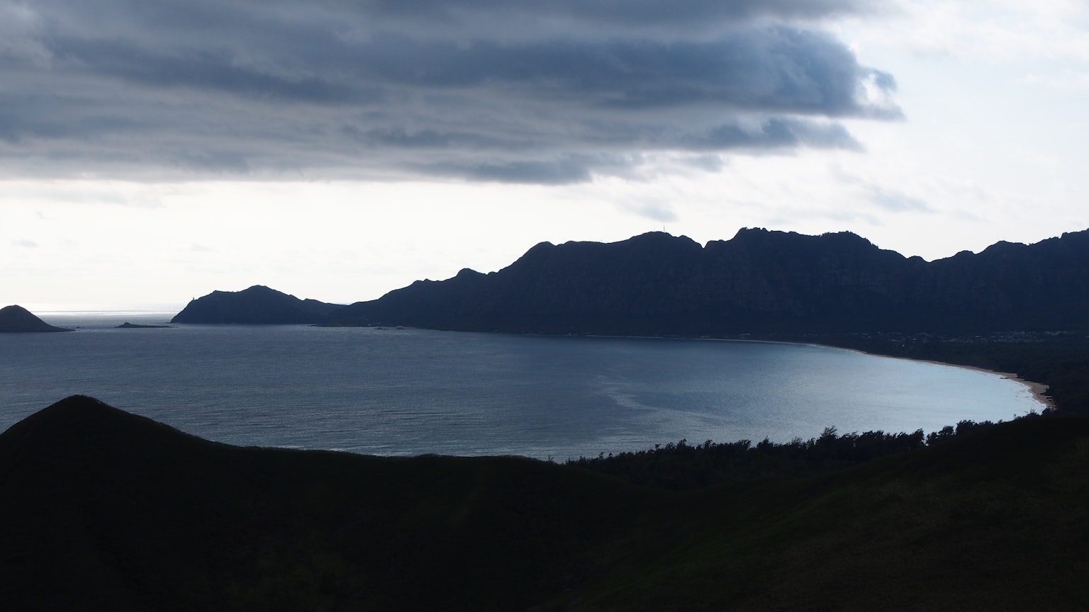 Dramatic coastal landscape with mountains under dark clouds