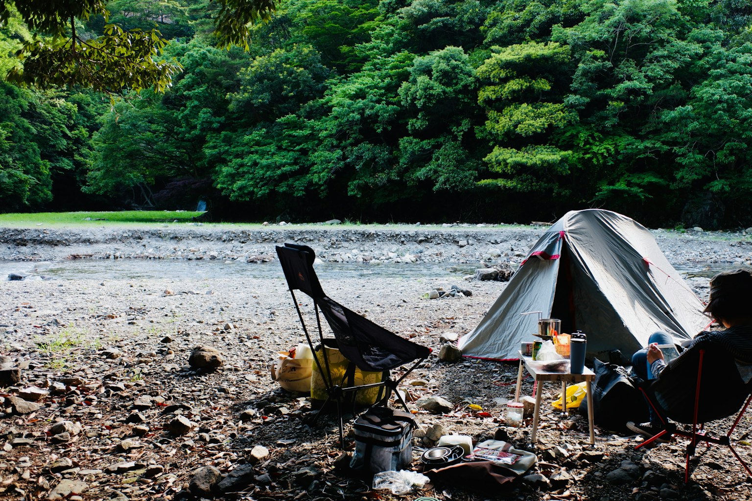 Kawasan perkemahan dekat sungai dengan tenda dan perlengkapan berkemah