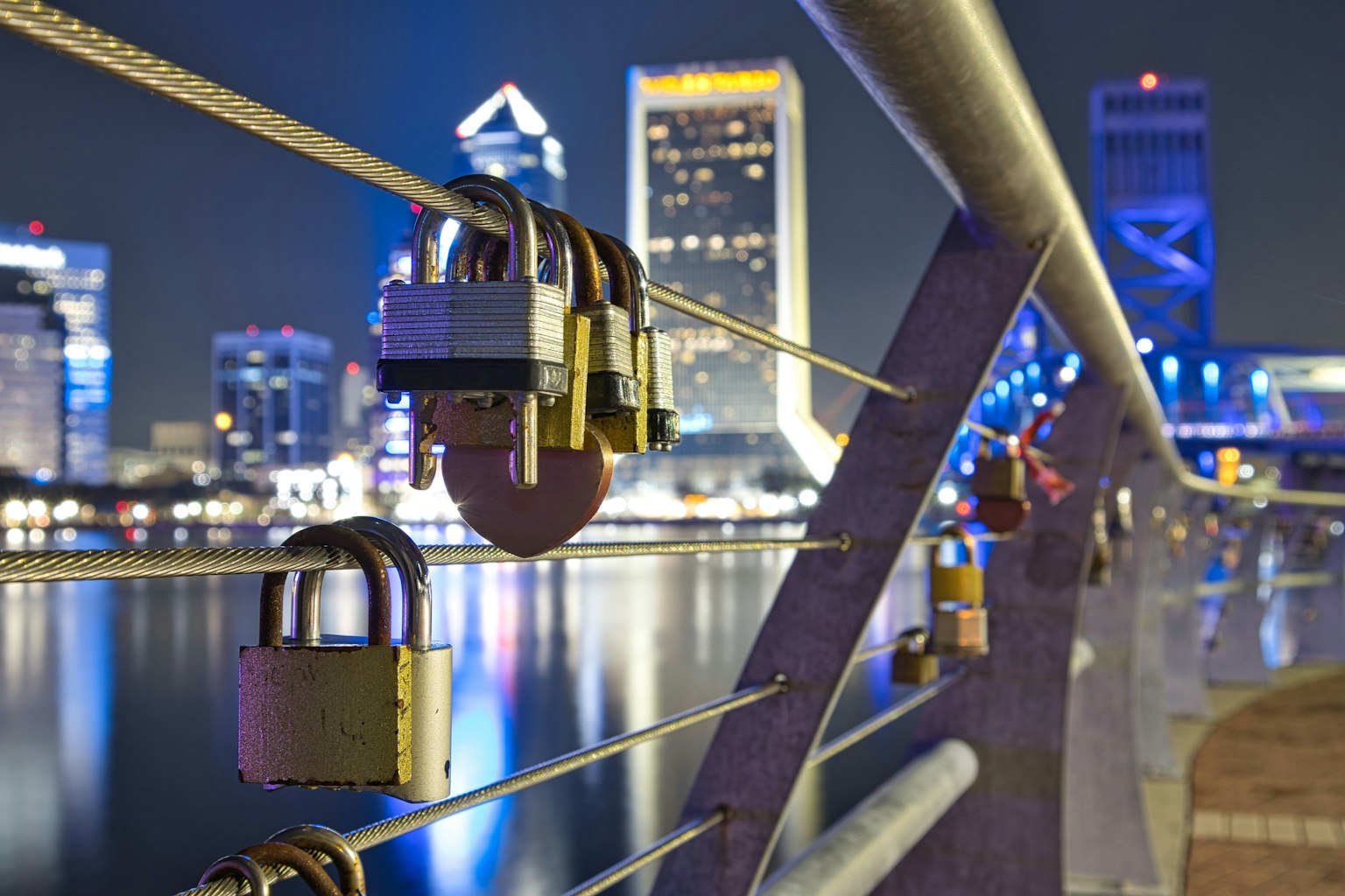 Blick auf eine Brücke mit Vorhängeschlössern vor der nächtlichen Skyline von Jacksonville