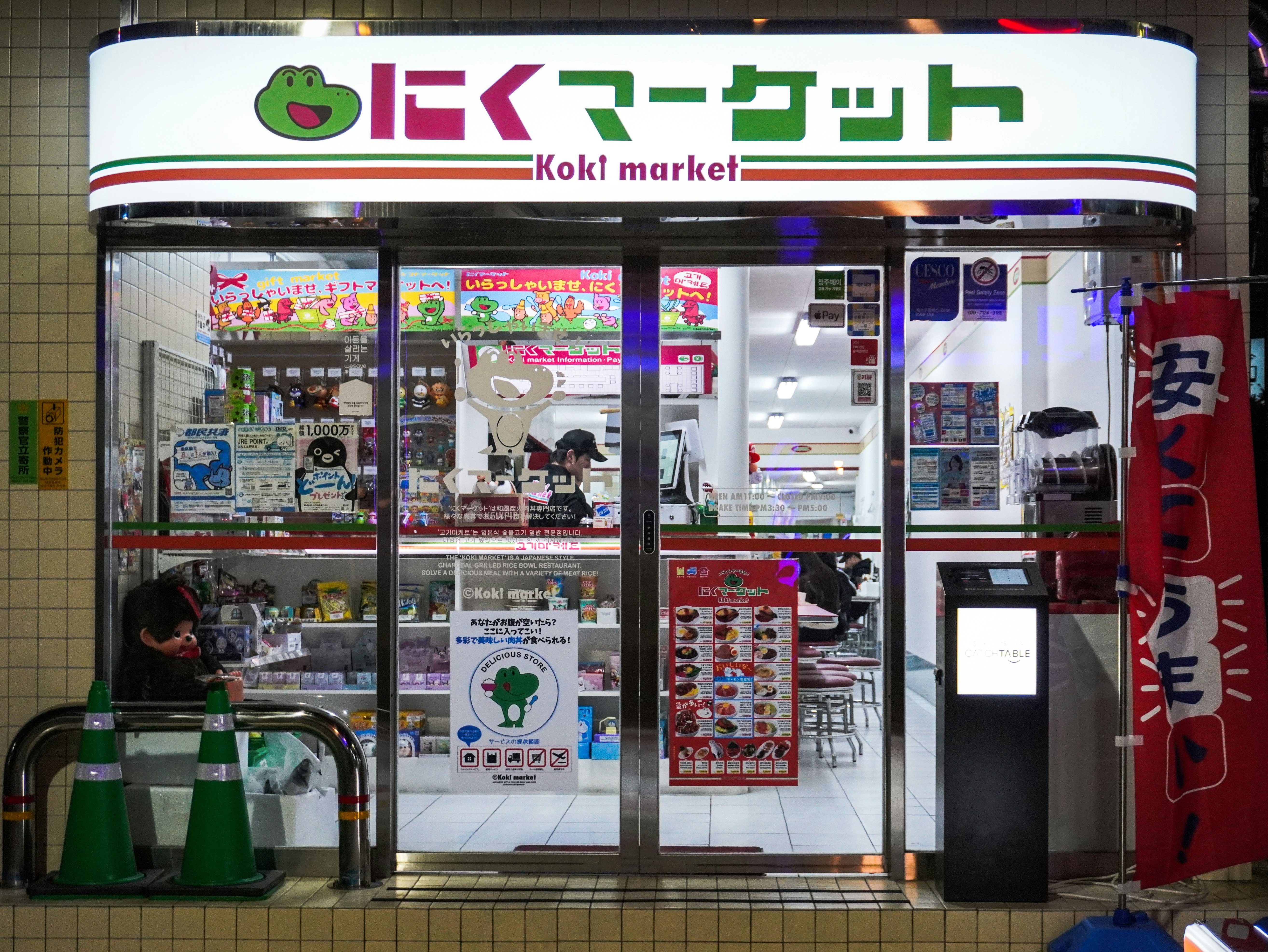 「Koki market」看板のある店頭の自動販売機と商品棚