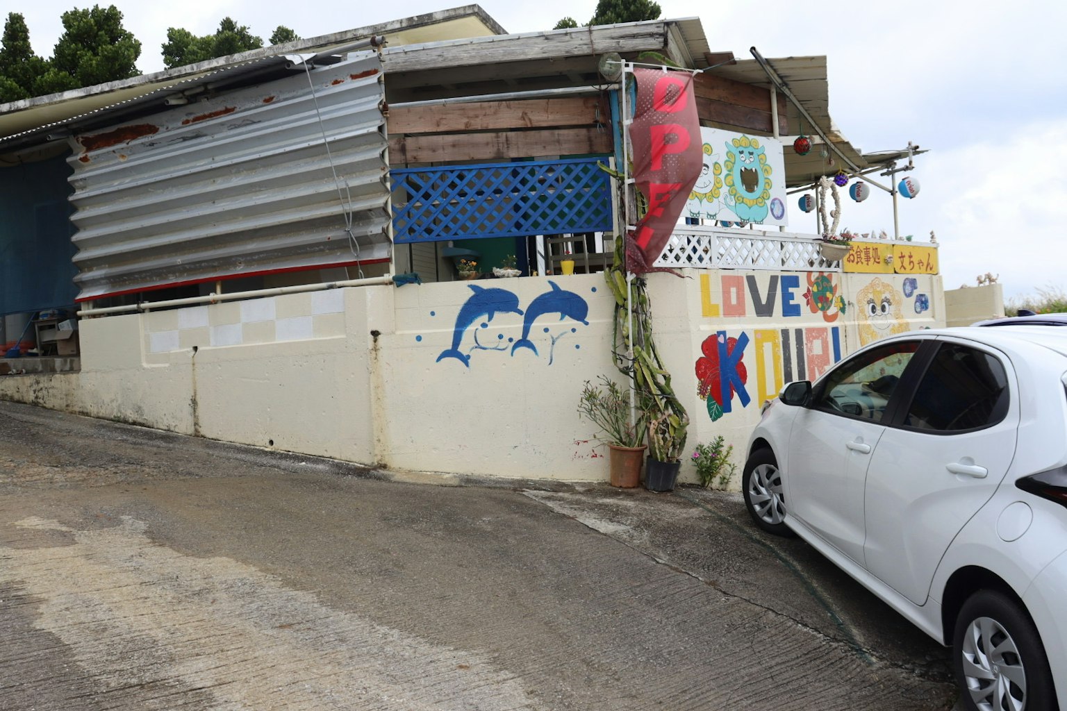 Exterior of a colorful building with murals and a white car