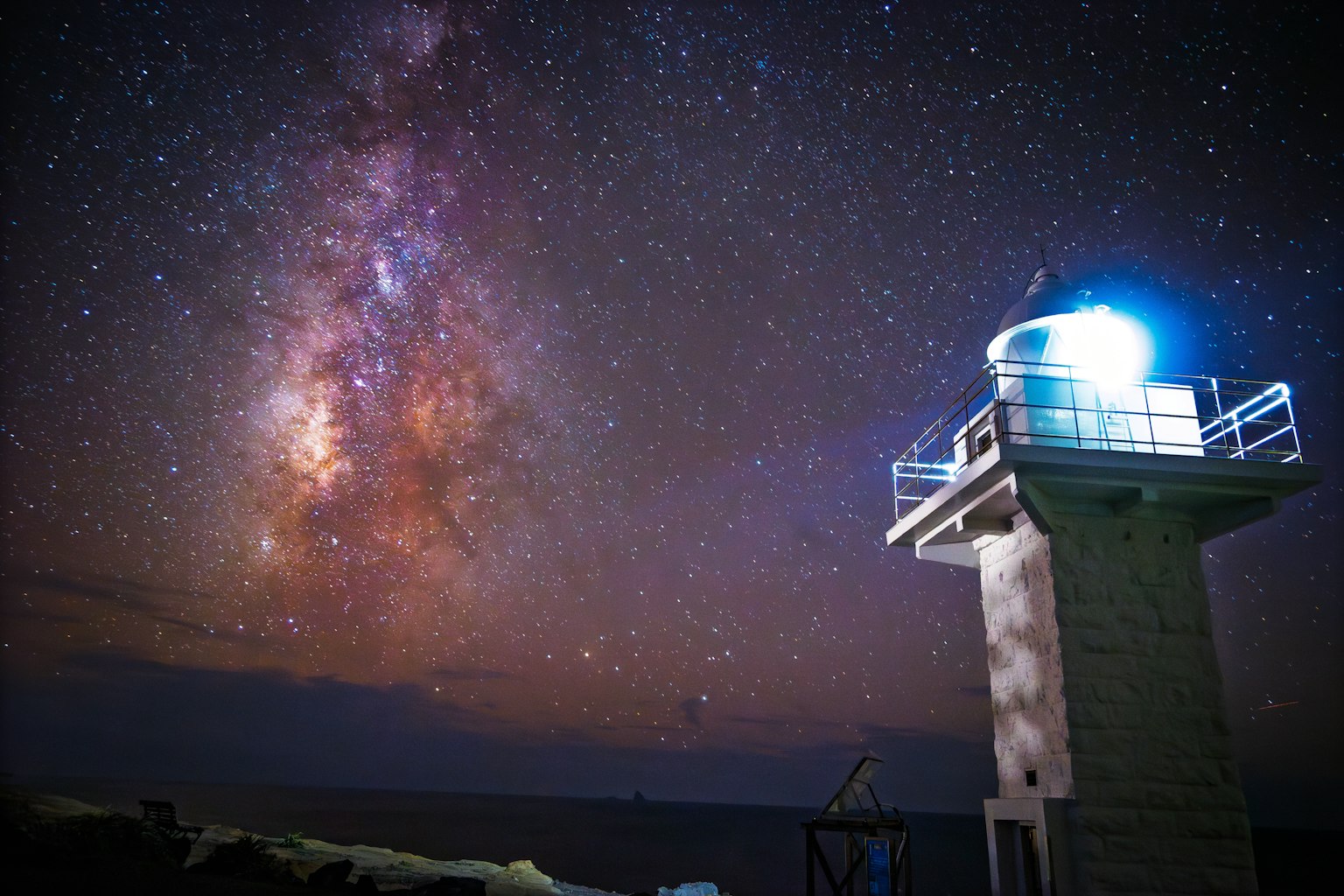 星空の下に立つ灯台と銀河の美しい景色