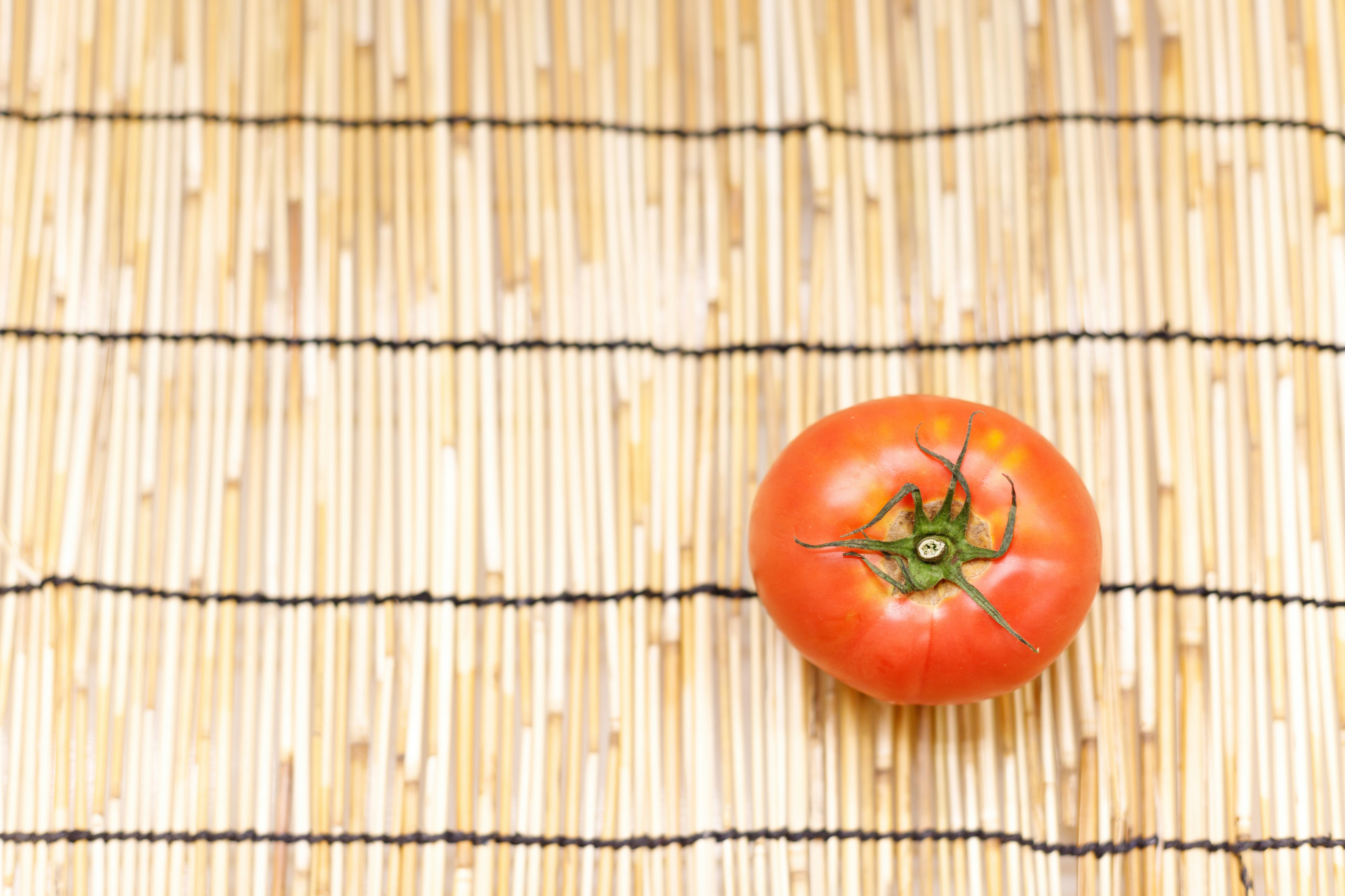 Tomate rouge posée sur un store en bambou