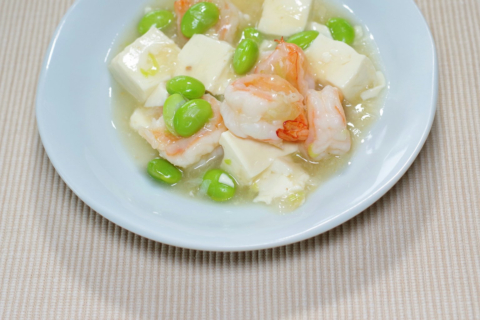 A dish featuring shrimp and tofu garnished with green beans