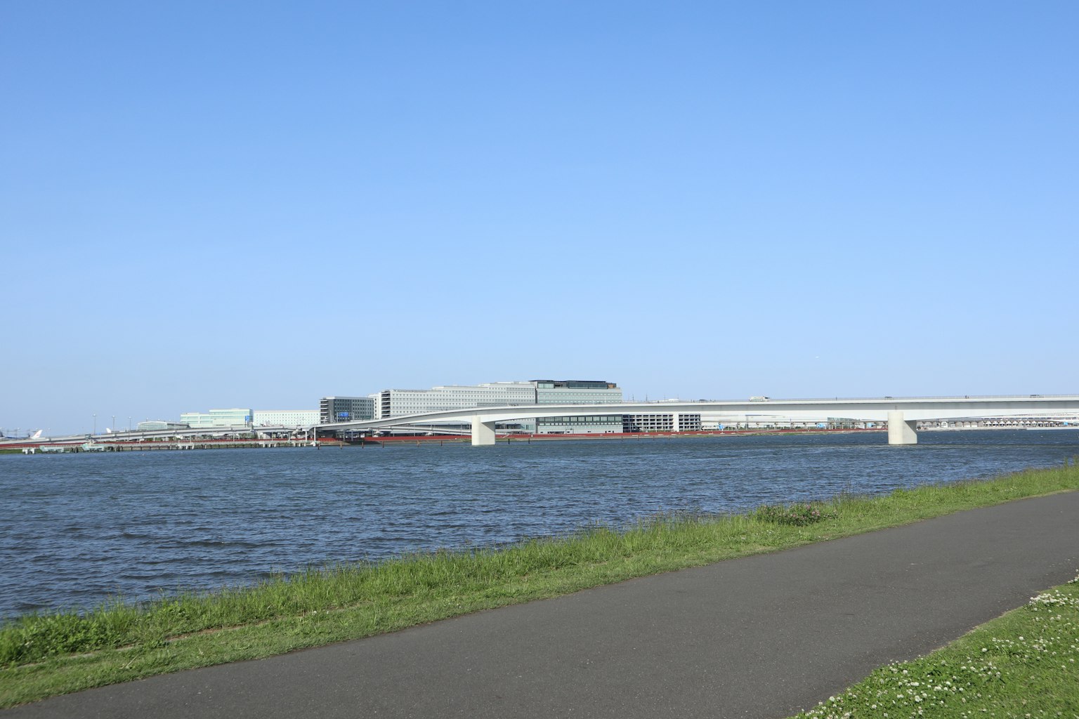 在晴朗的藍天下，河流和步道的風景以及遠處的建築