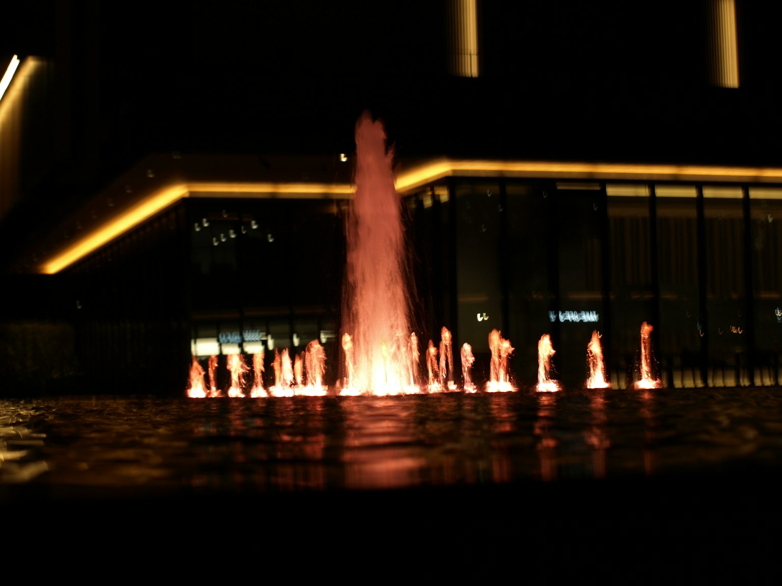 Ein schöner, beleuchteter Brunnen bei Nacht vor einem Gebäude