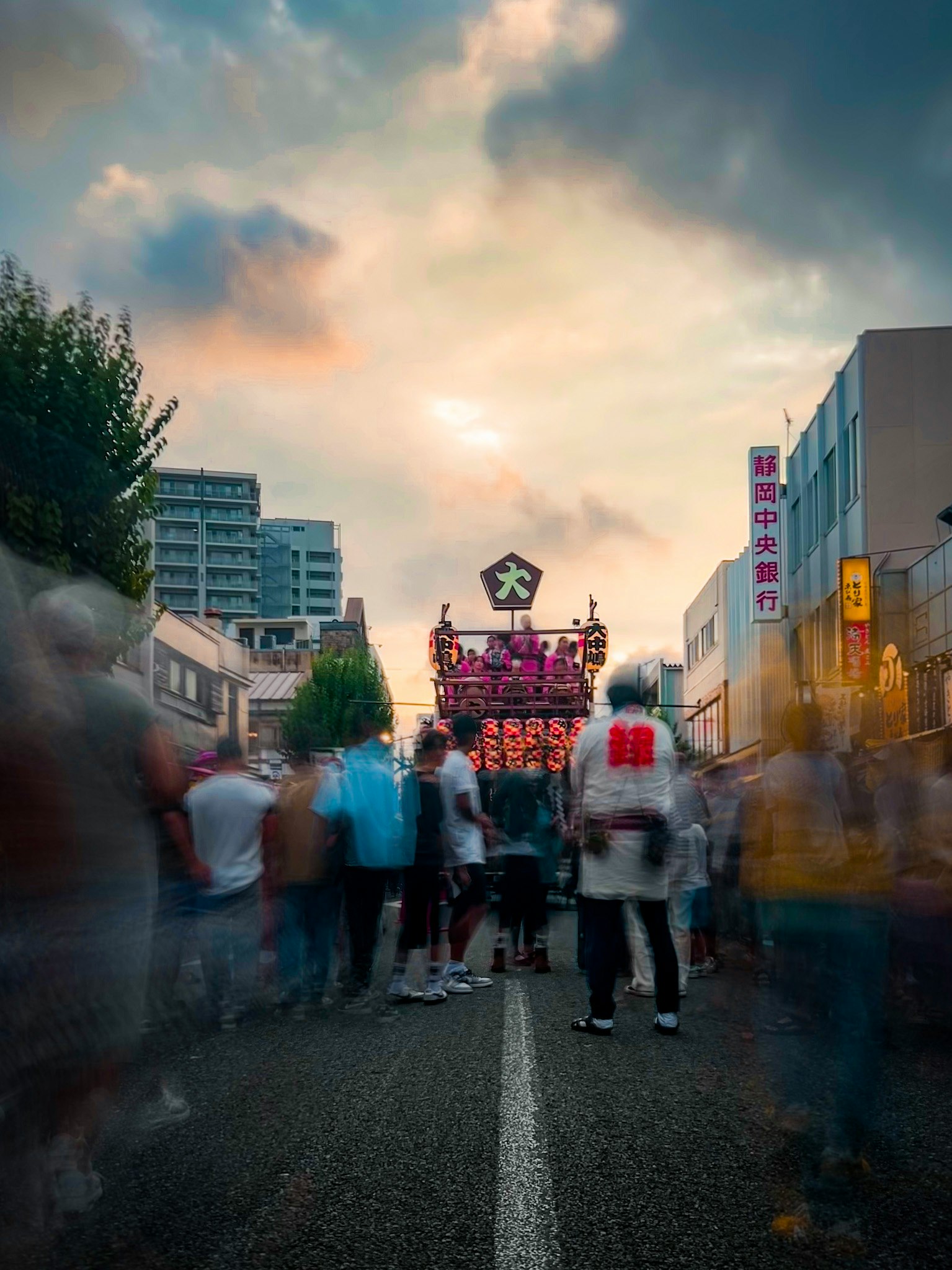 Lebhafte Festivalszene mit Menschenmengen in bunten Outfits unter einem Sonnenuntergangshimmel