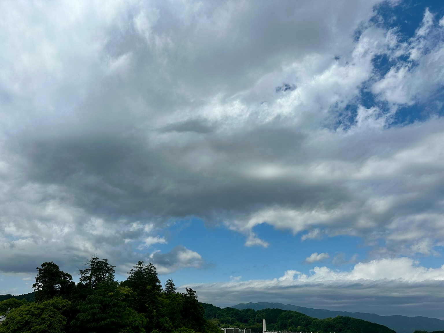 Vista panoramica del cielo blu con nuvole bianche sopra colline verdi