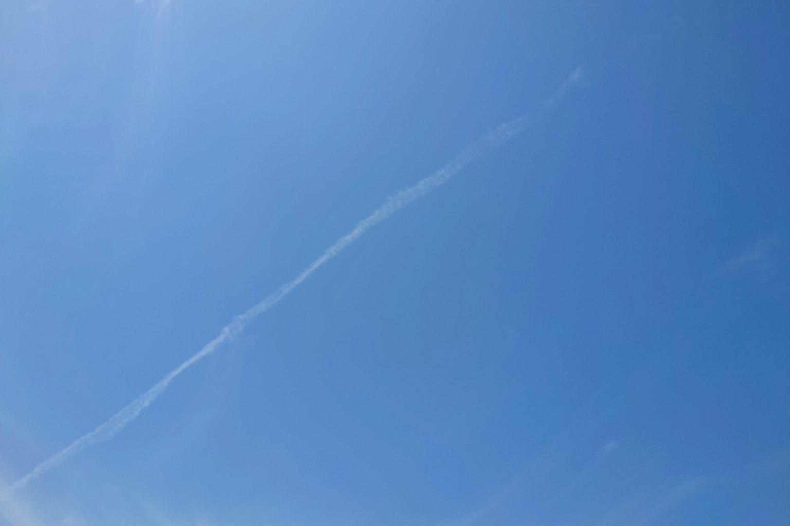 Klarer blauer Himmel mit einer weißen Kondensstreifen