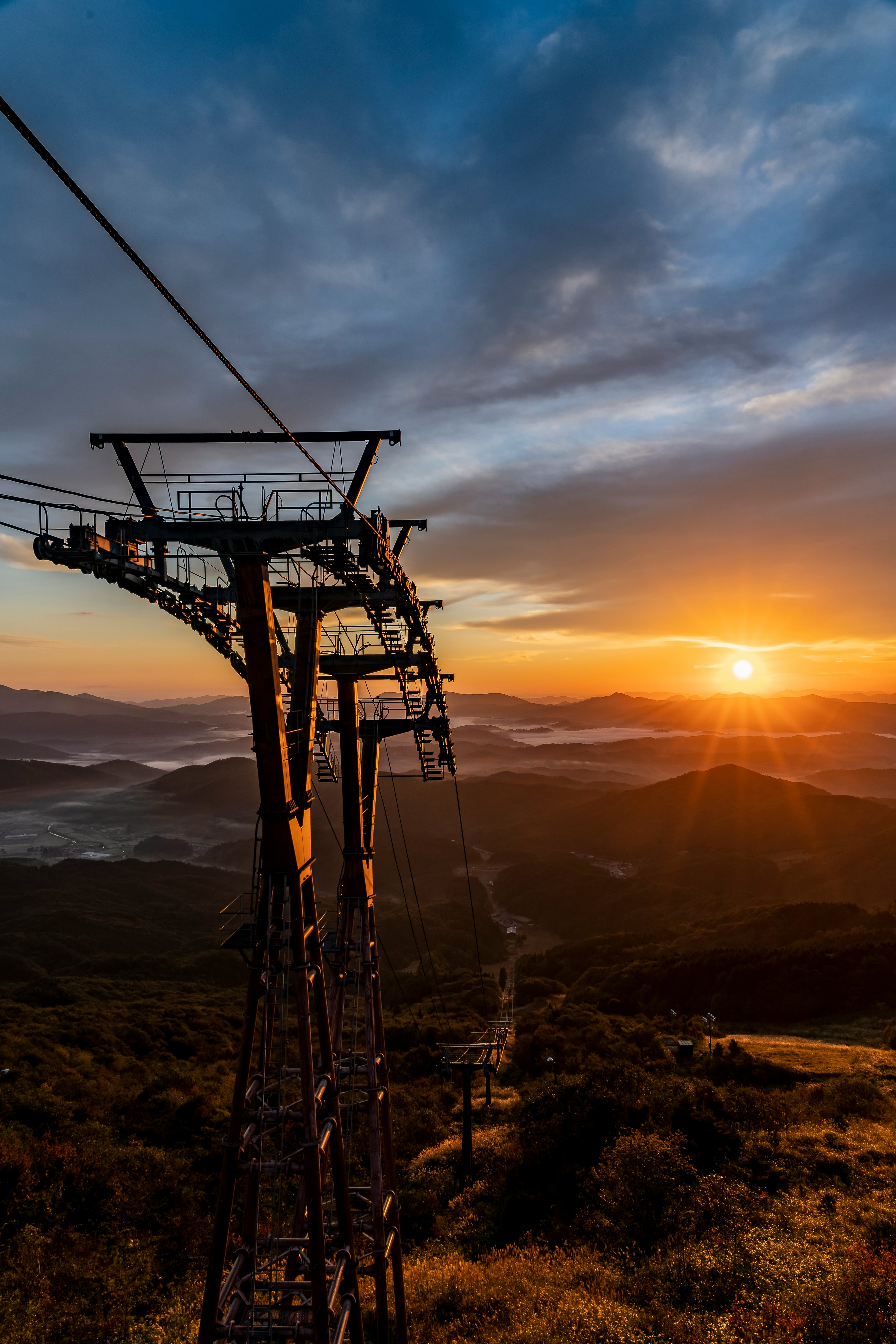 vue de montagne au coucher du soleil avec un pylône de téléphérique et ses câbles