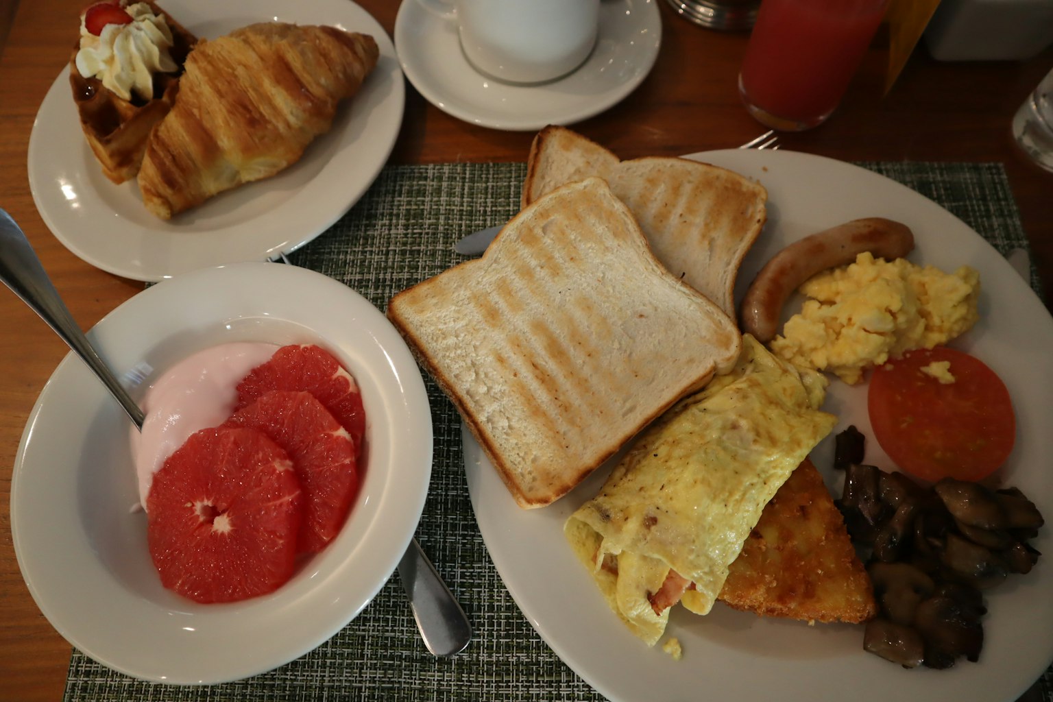 Plato de desayuno con tostadas, tortilla, tocino, pomelo y yogur