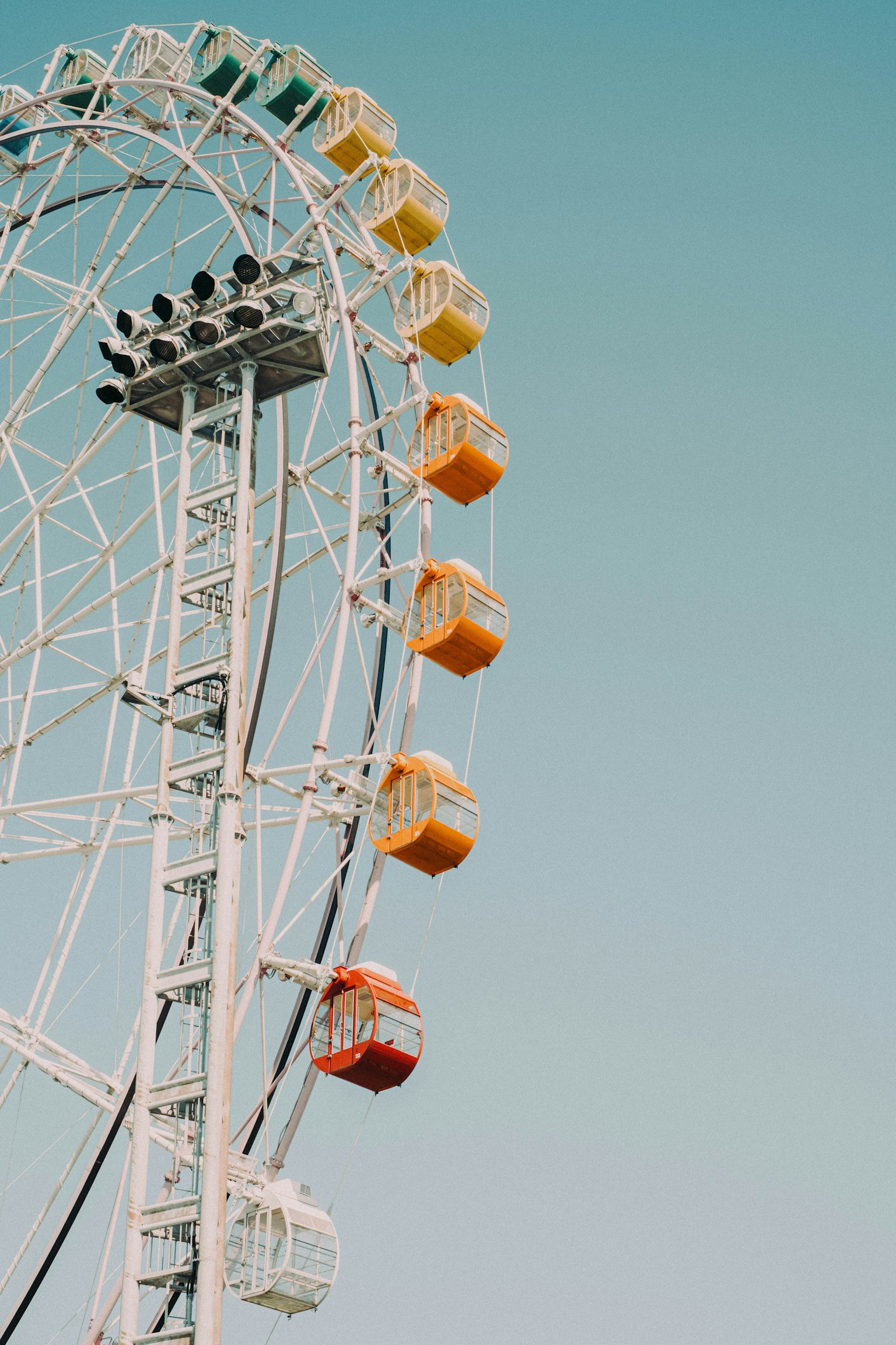 Vue latérale d'une grande roue avec des cabines colorées sous un ciel bleu