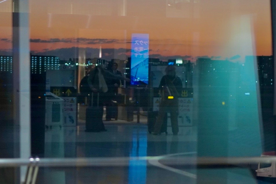 空港の窓越しに見える夜景と人影のあるターミナル