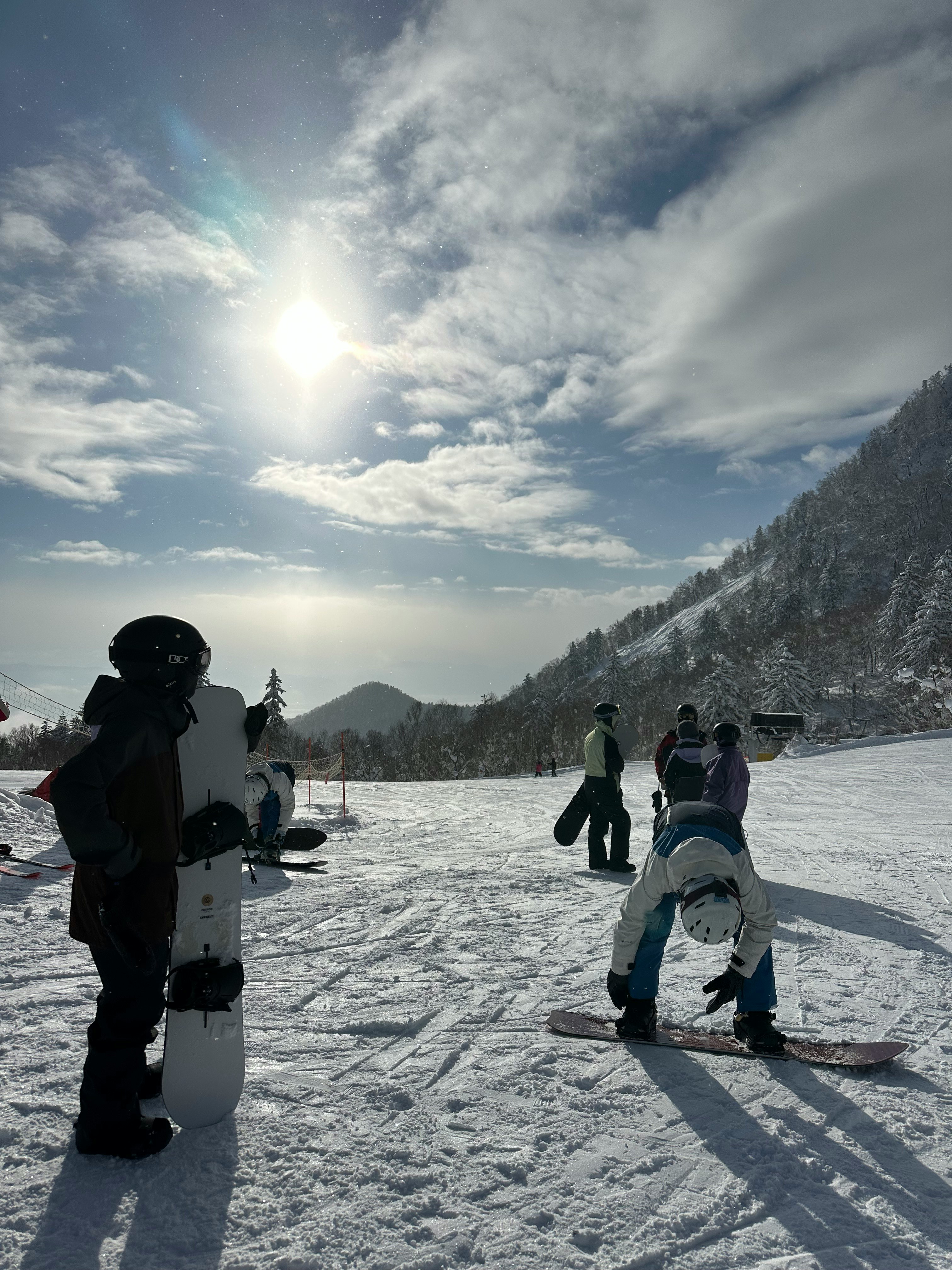 富良野の雪原でスノーボードを楽しむ人々のシルエット