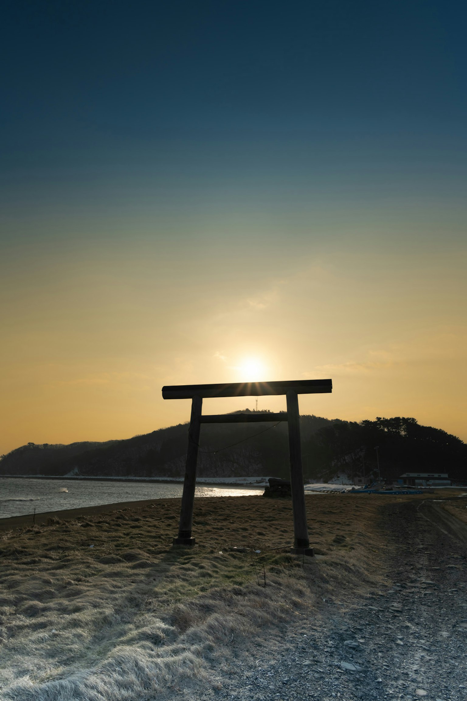 夕陽下的鳥居與沙灘和海水的剪影