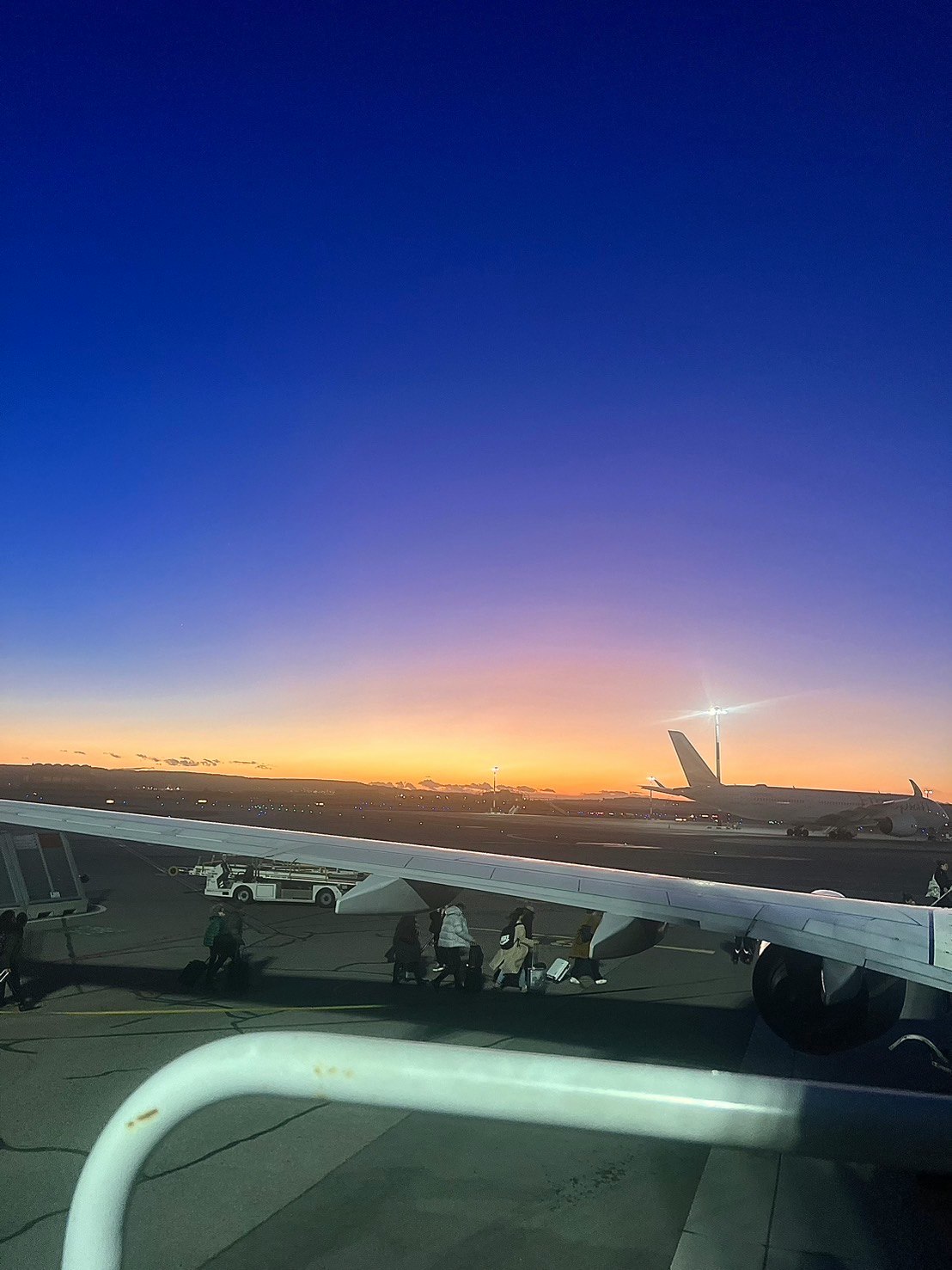 夕焼けの空港で飛行機の機内から見える滑走路と海