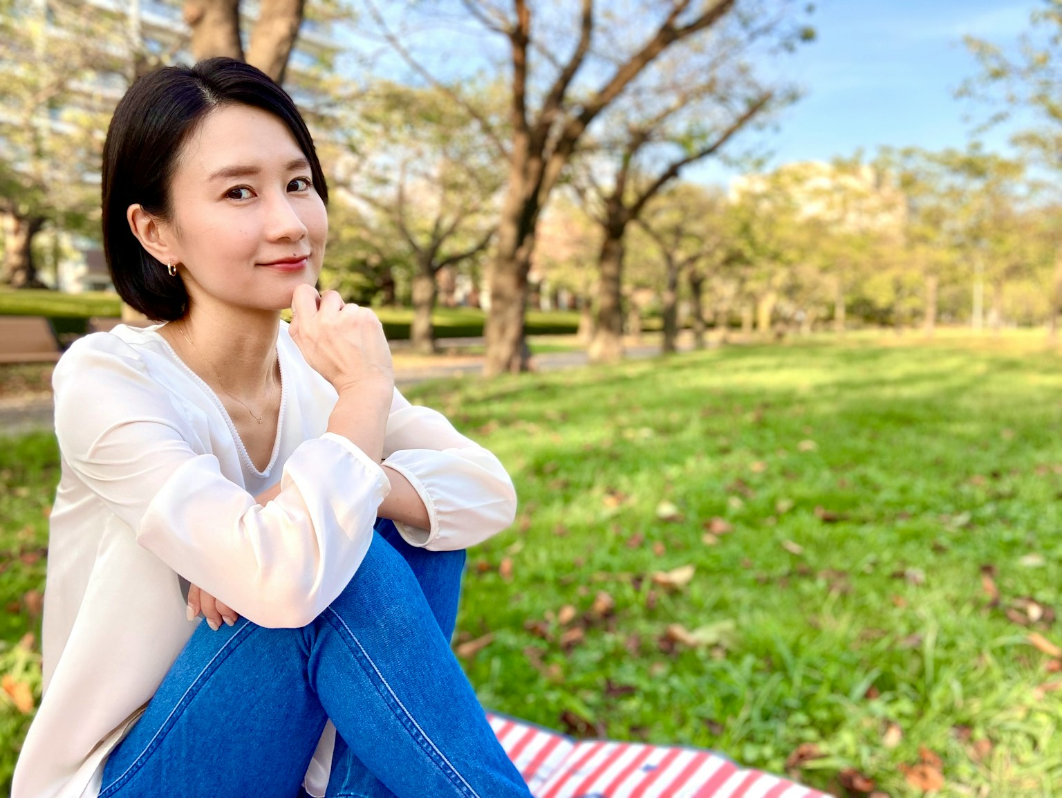 공원에서 풀밭에 앉아 미소 짓고 있는 여성