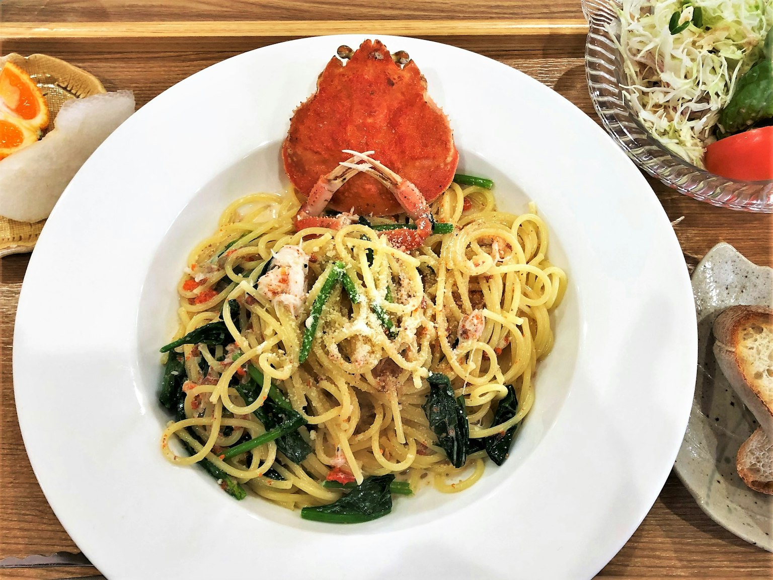 Un piatto di spaghetti guarnito con granchio e verdure