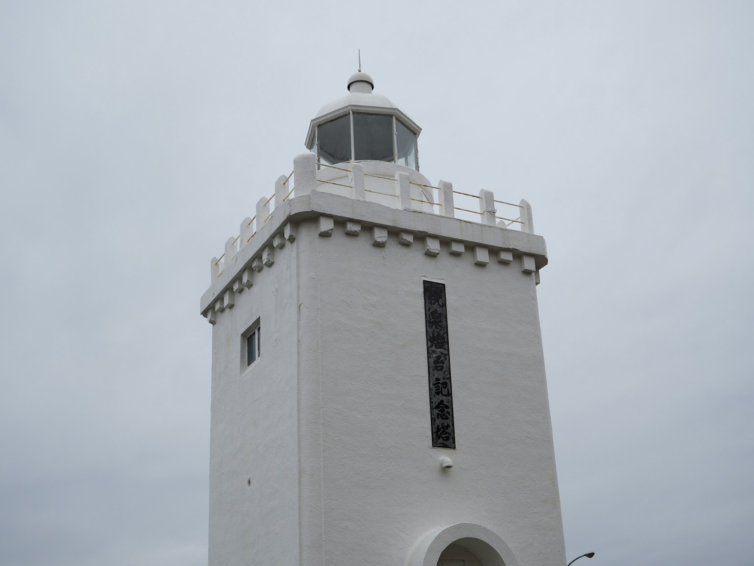 Torre de faro blanca de pie bajo un cielo gris