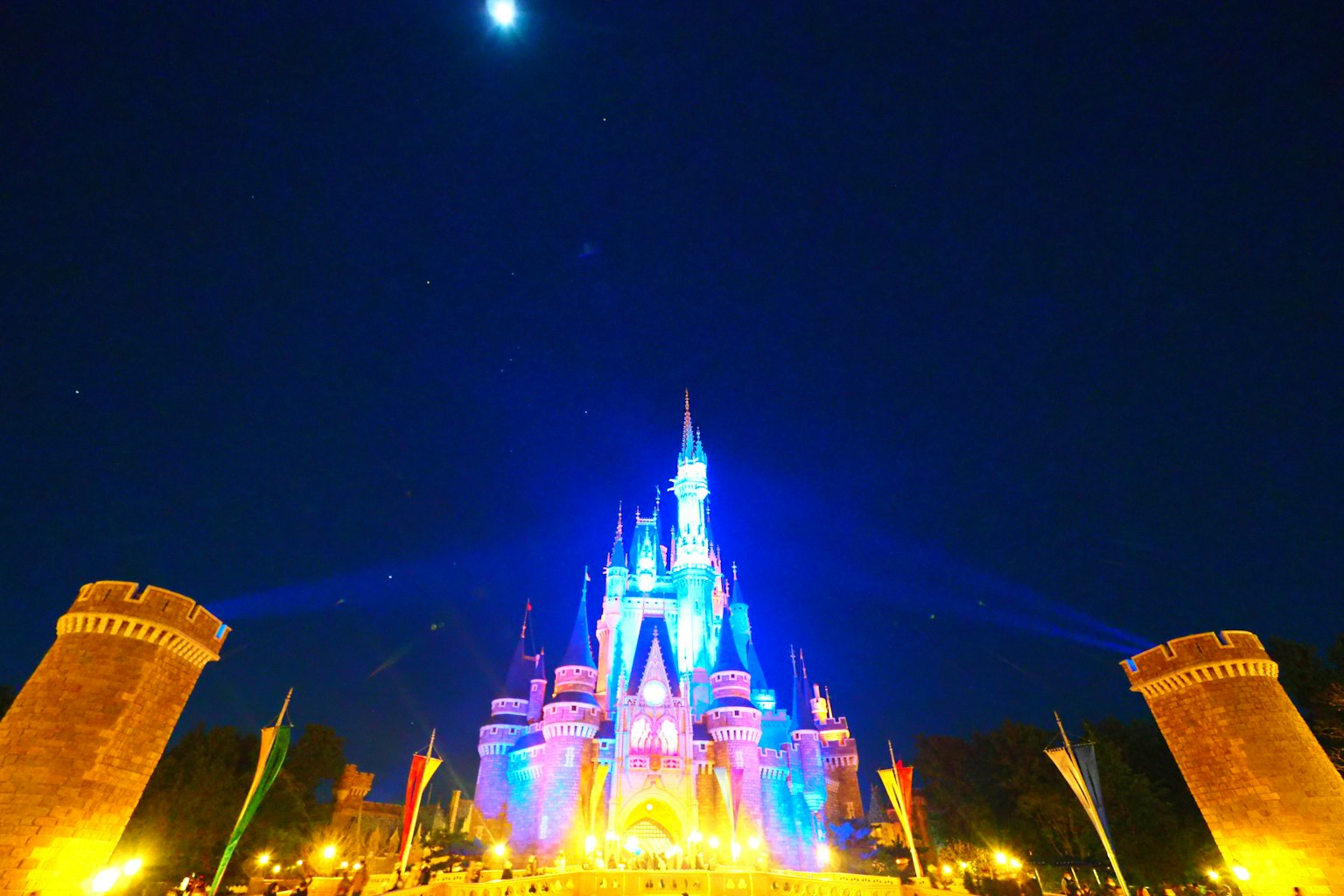 Kastil Disney yang diterangi di malam hari dengan lampu biru dan ungu yang cerah